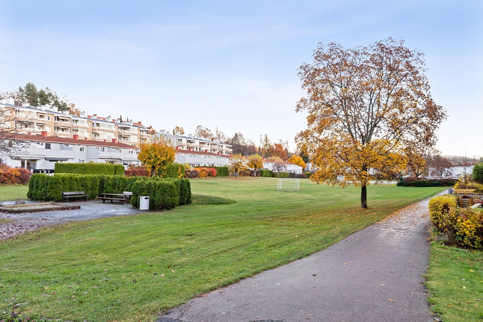 Pent opparbeidet uteområde med gressplener, prydbusker, sittegrupper og lekeareal. Galleribilde