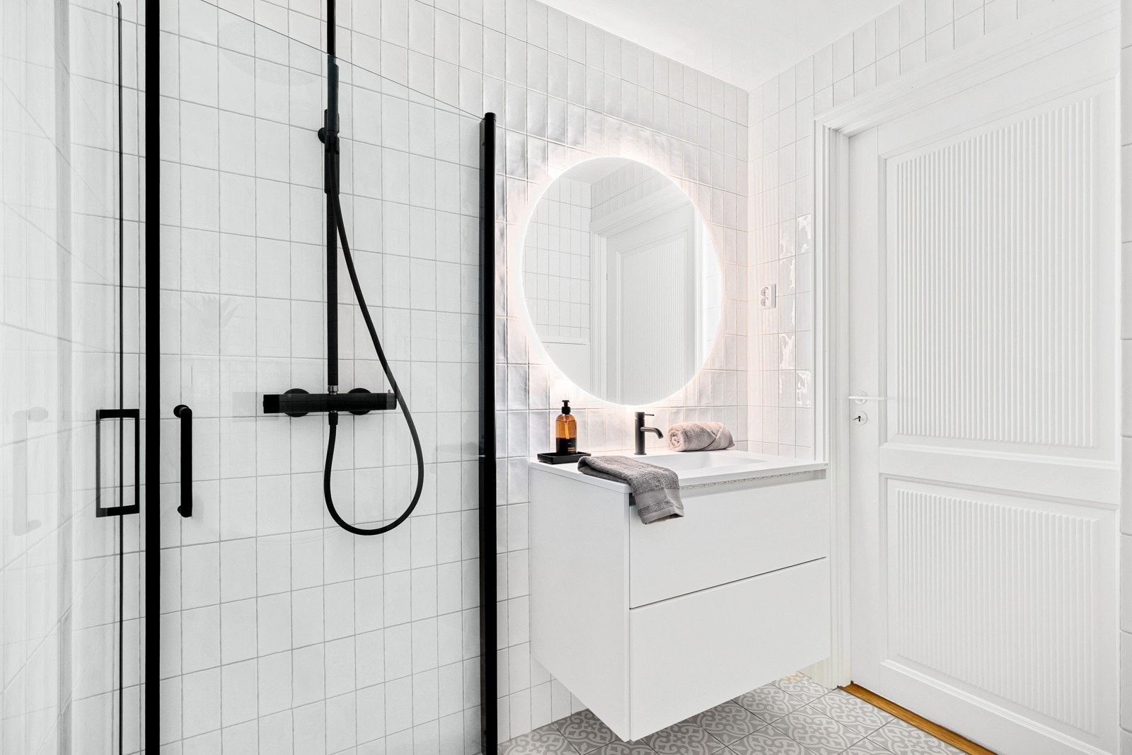 Helfliset bad med av innfelbare dusjdører, servant med innredning, speil med lyskant og wc. Galleribilde