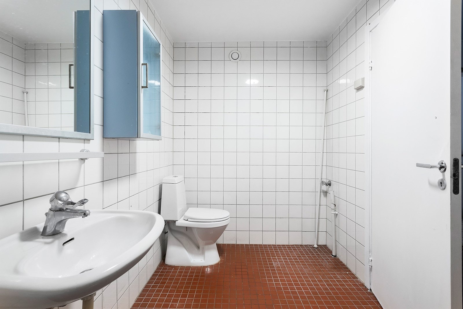 Fliselagt baderom med dusjhjørne, wc, servant og opplegg for vaskemaskin. Galleribilde