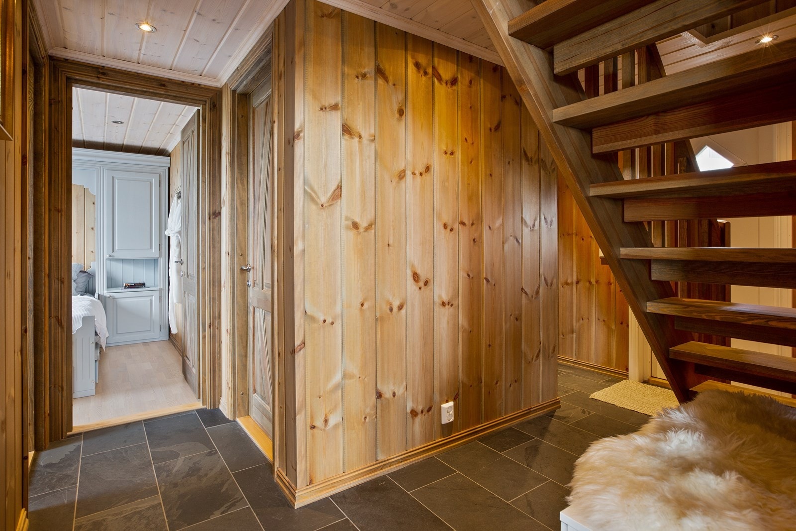 Pent inngangsparti med grå gulvfliser og beisede panelvegger. Galleribilde