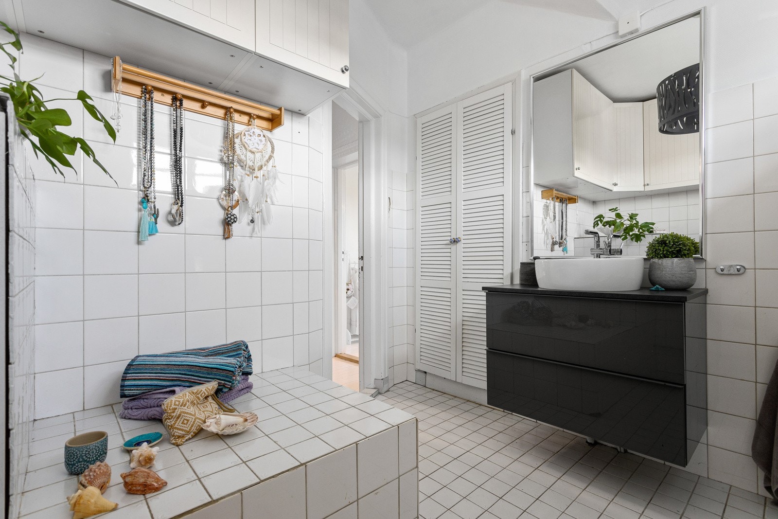 Badet er utstyrt med wc og servant med skuffer under. Det er flislagt gulv og vegger. Galleribilde