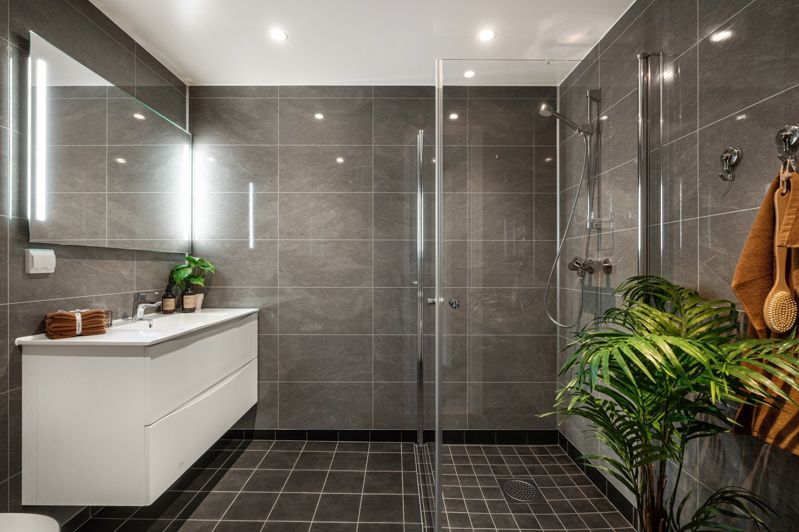 Badet innredes med vegghengt toalett, dusjhjørne og servant med innredning Galleribilde