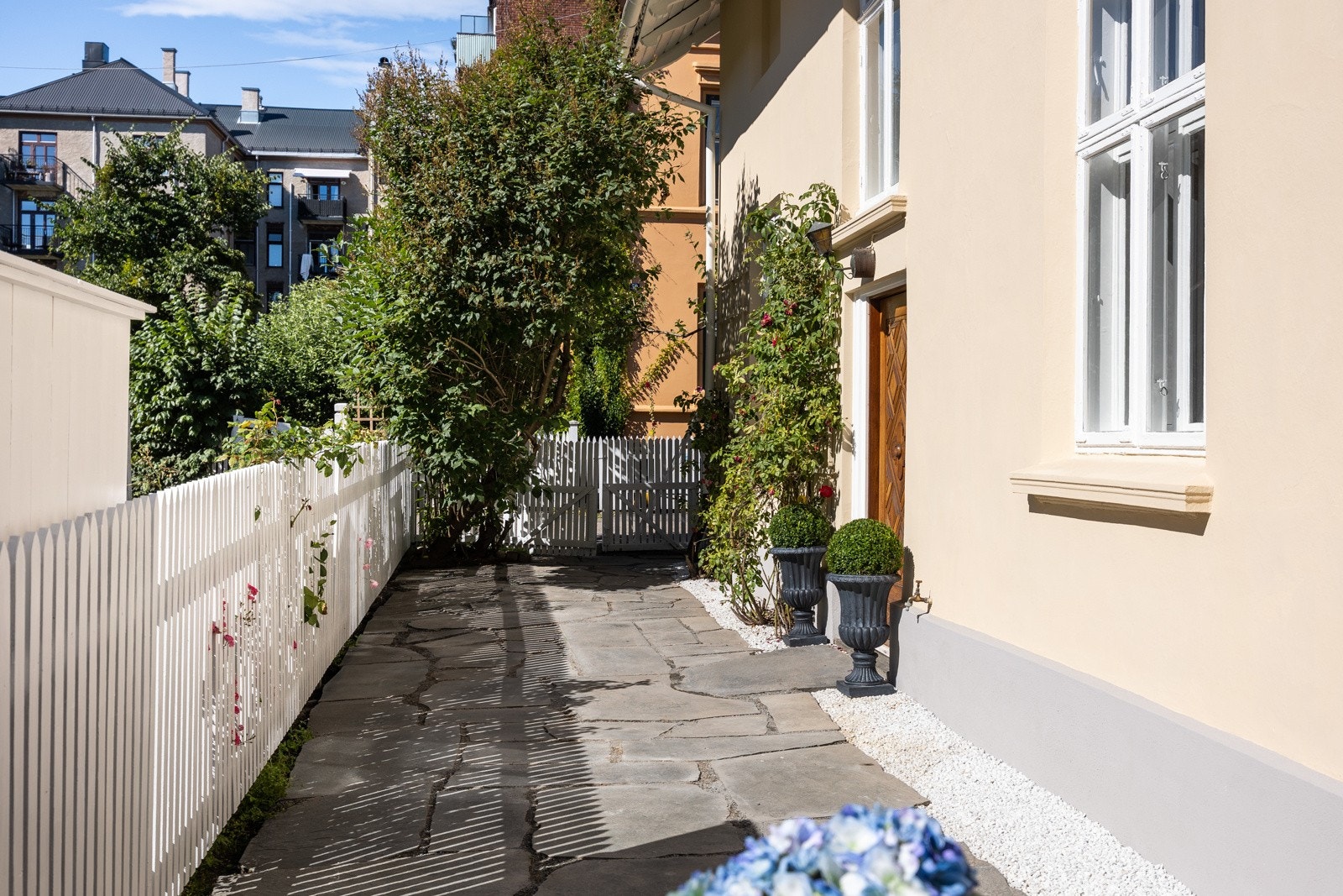 Boligen har et sjarmerende inngangsparti med skiferlagt adkomst, vakker beplantning og tidstypisk ytterdør. Galleribilde