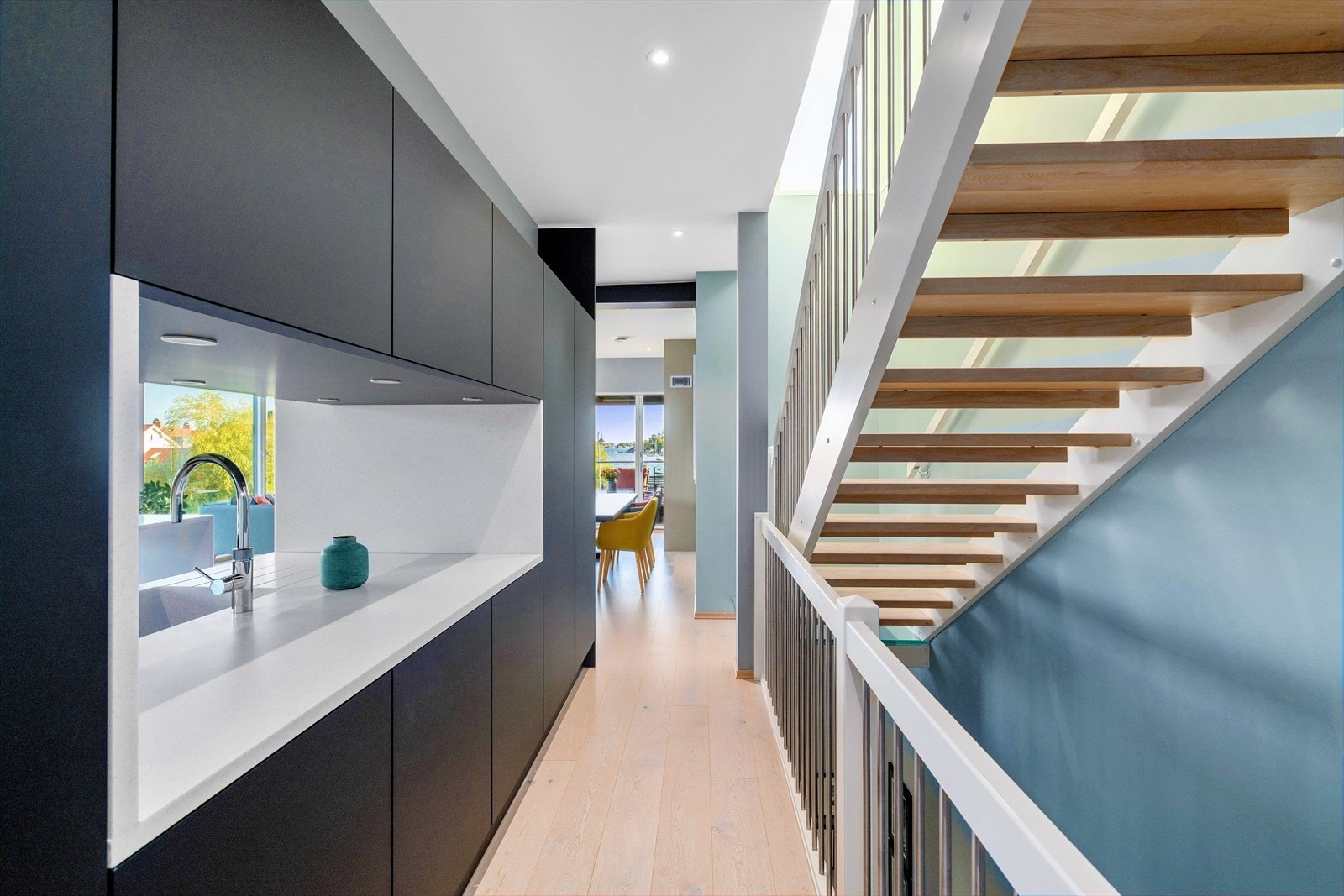 Kjøkkenskapene danner en vegg med åpning mellom trappeløp og kjøkkendelen Galleribilde