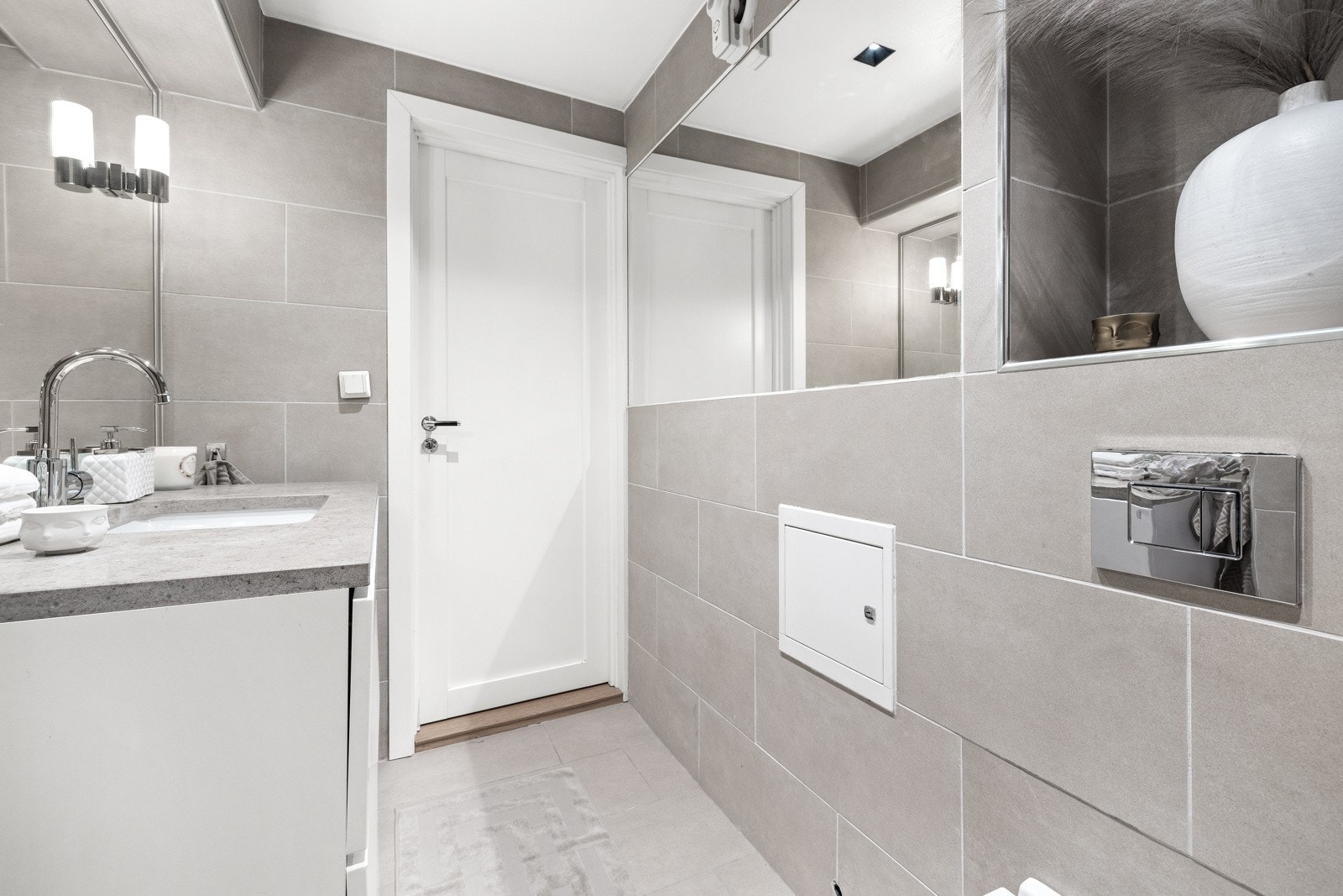 Innredningen består av skap med servant, speil med lampetter, vegghengt toalett og dusj med foldedør. Galleribilde