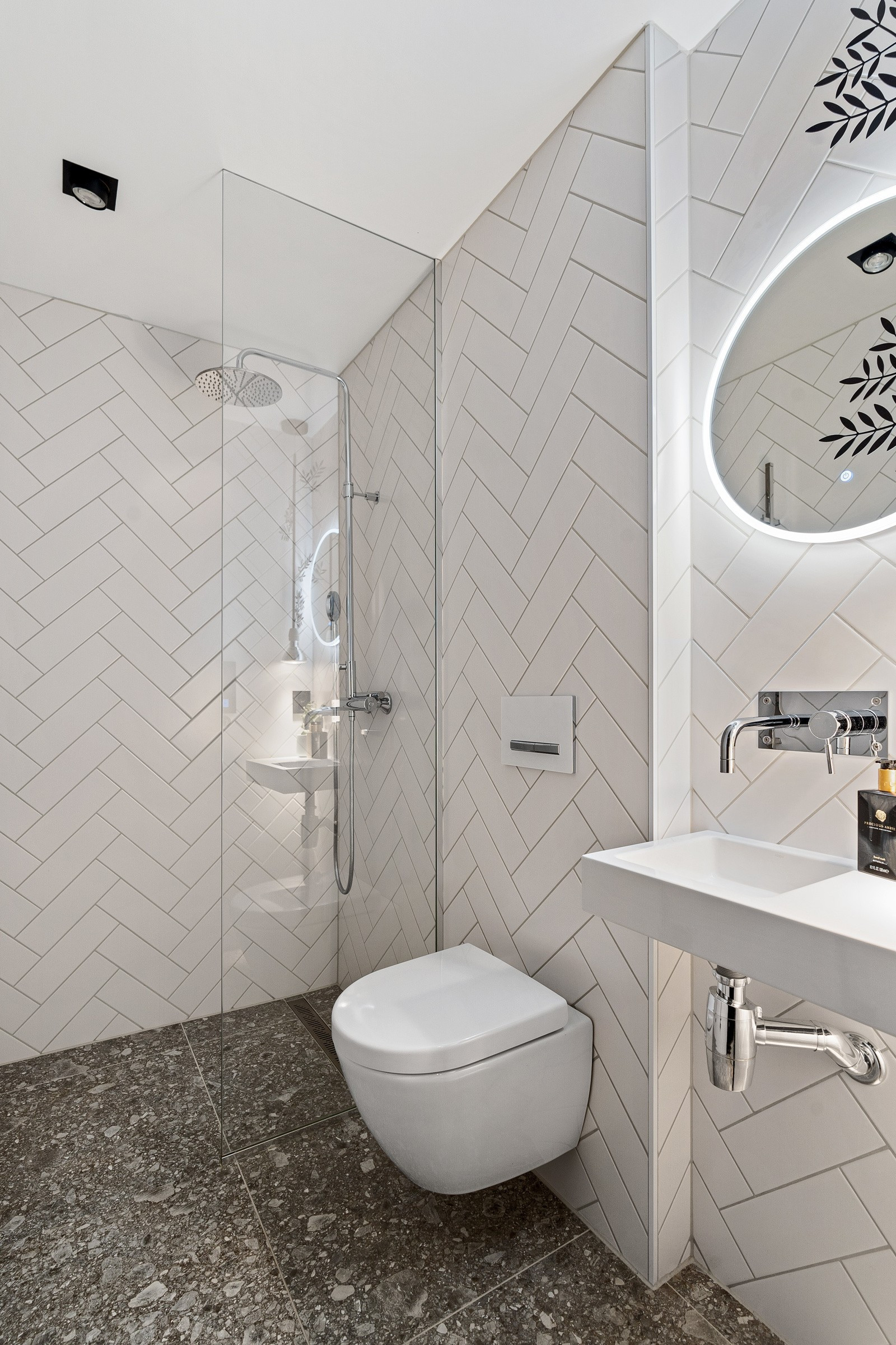 Badet i 1. etasje er komplett flislagt og er innredet med servant, vegghengt toalett og dusjhjørne.