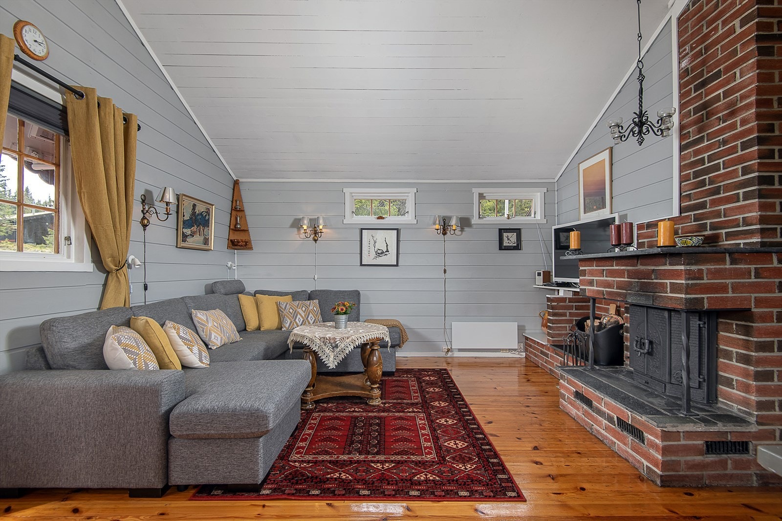 Sentralt i rommet er det en peis, der knitrende flammer kan nytes fra et hyggelig sofahjørne. Galleribilde