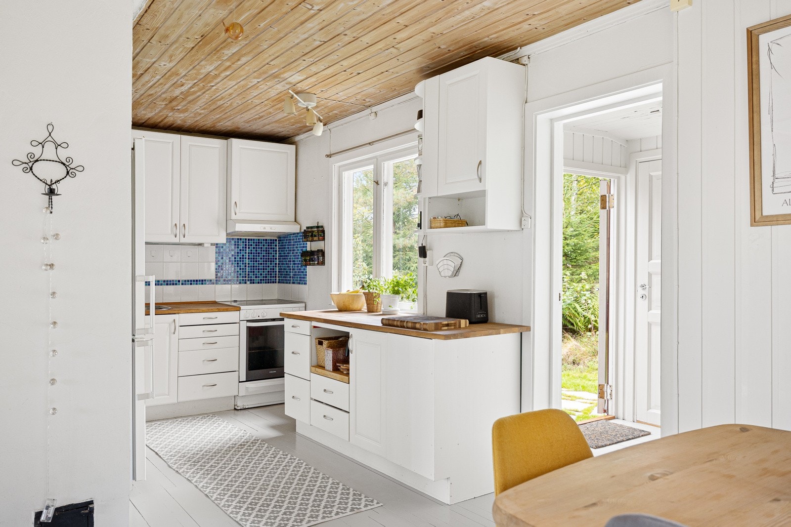 Lyst og skjermet kjøkken. Innredning med profilerte fronter og heltre benkeplate. Galleribilde