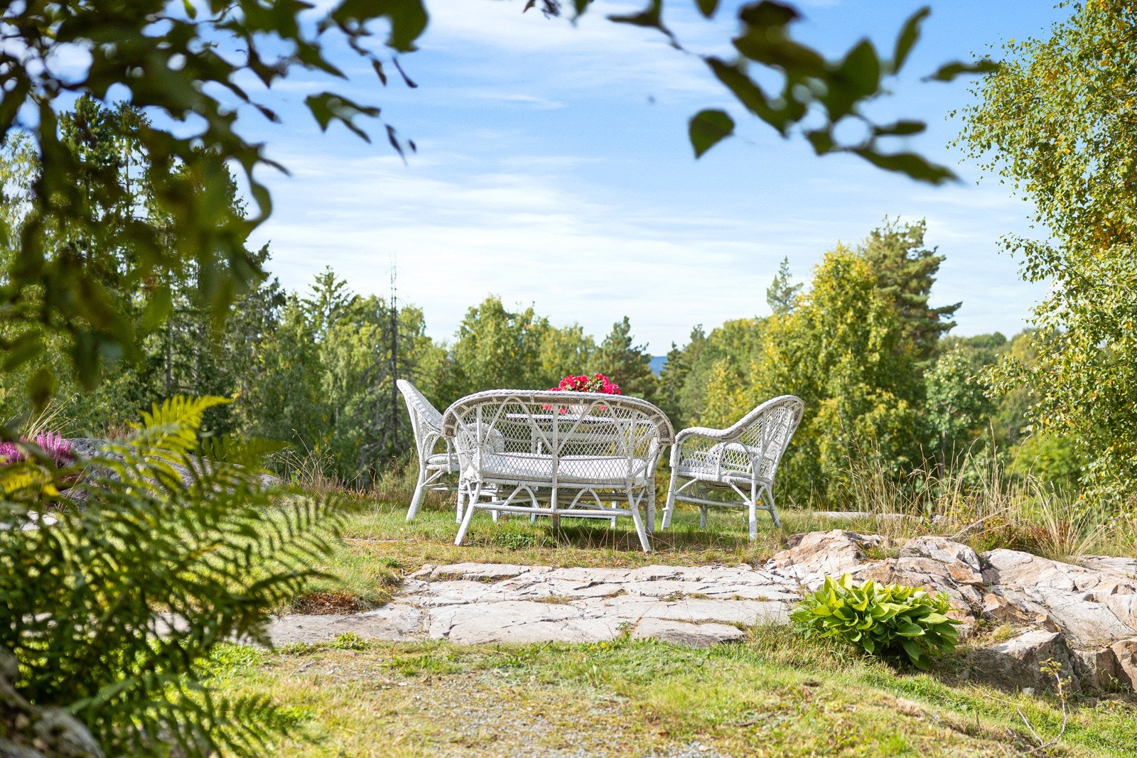 Fritidseiendommen er omkranset av grønn og frodig beplantning. Galleribilde