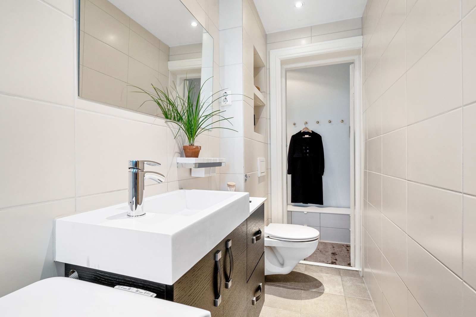 Badet i leiligheten er flislagt i lyse toner og har varmekabler i gulv. Galleribilde