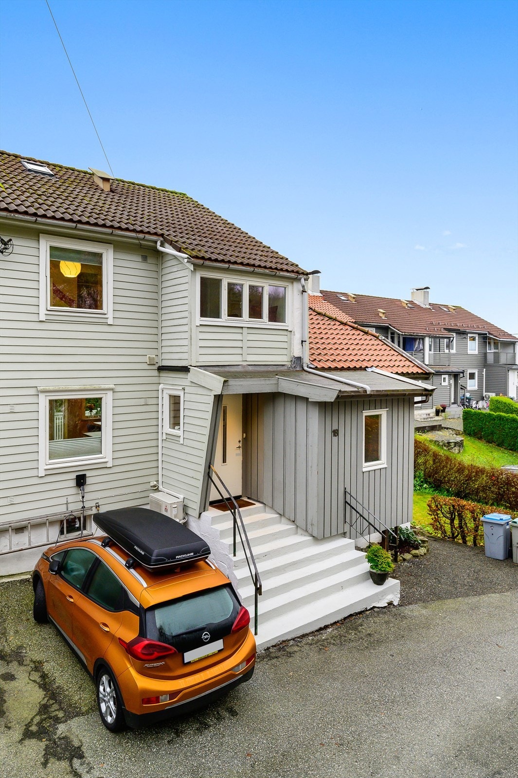 Ved husets inngangsparti er det biloppstillingsplass med el-bil lader. Tomten strekker seg også over veien på andre siden, og man har biloppstillingsplass til totalt to biler. Galleribilde