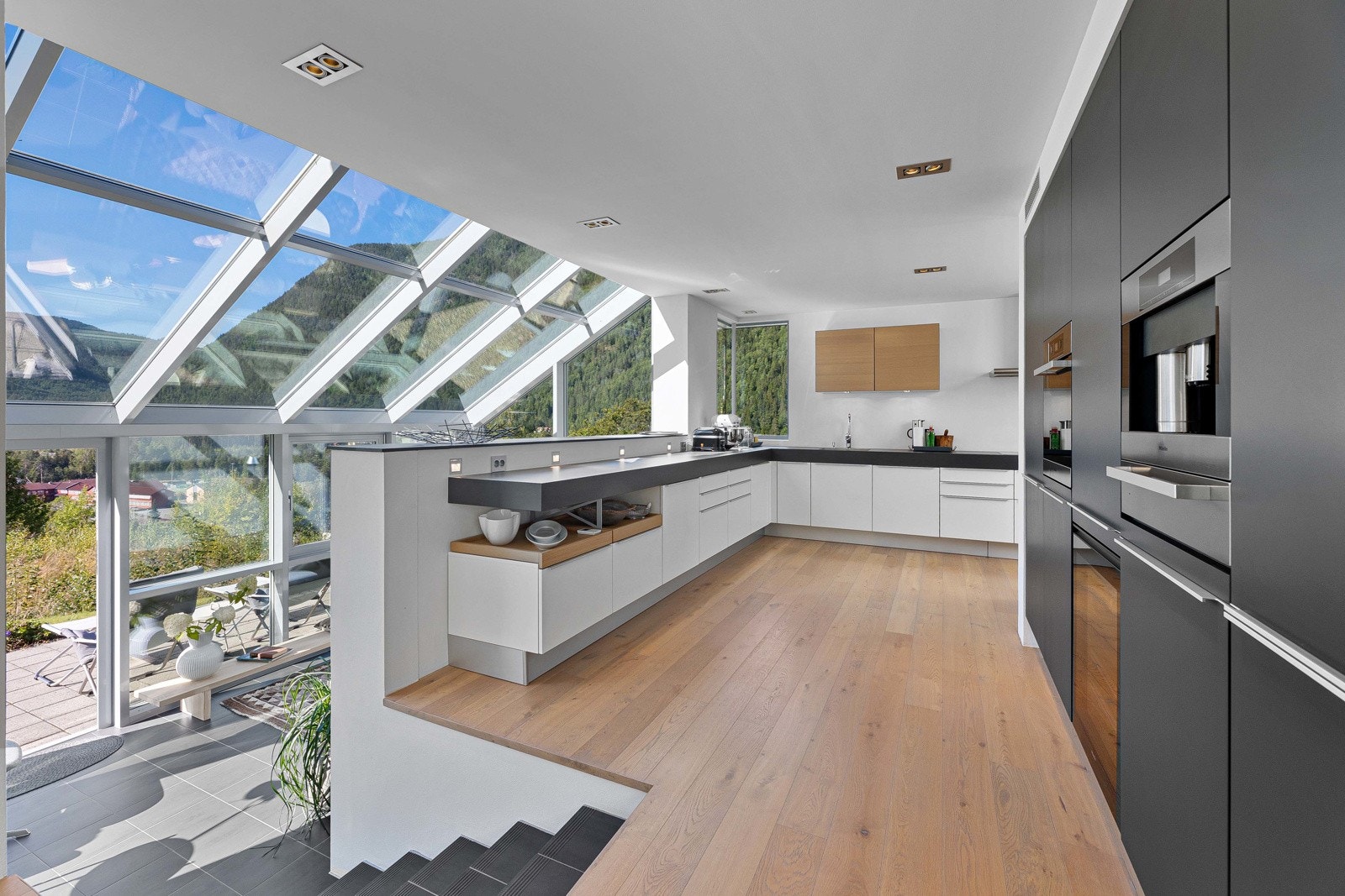 Åpen stue og kjøkkenløsning med nedgang til innglasset sommerstue Galleribilde