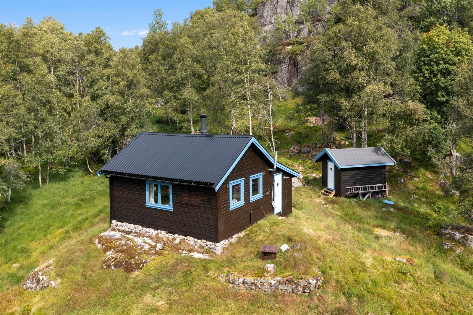Hytta ligger fint til i terrenget og trærne er med på å skjerme for vær og vind. Galleribilde