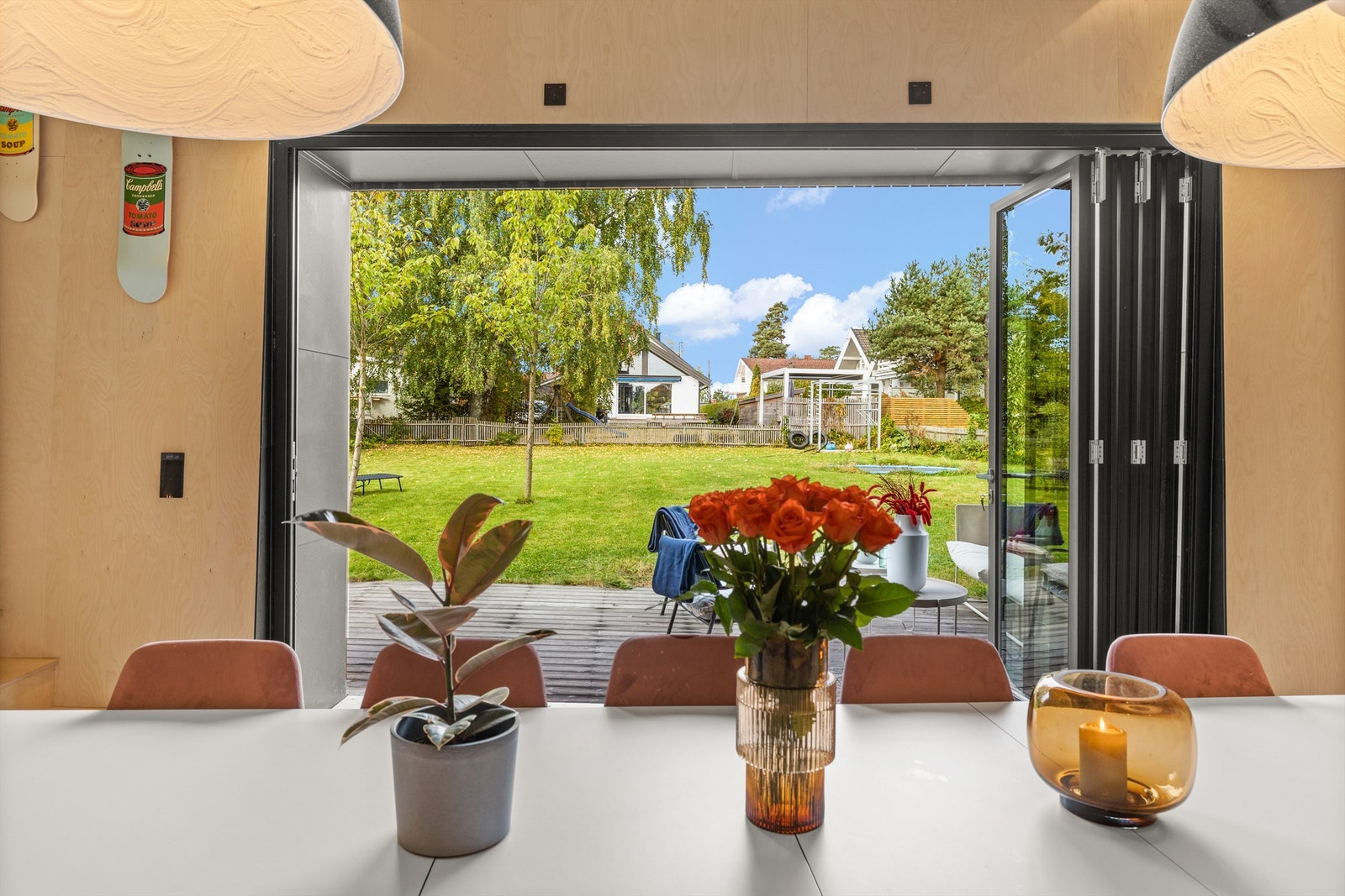 Utgang fra kjøkkenet via foldedører til stor og solrik terrasse og hage Galleribilde