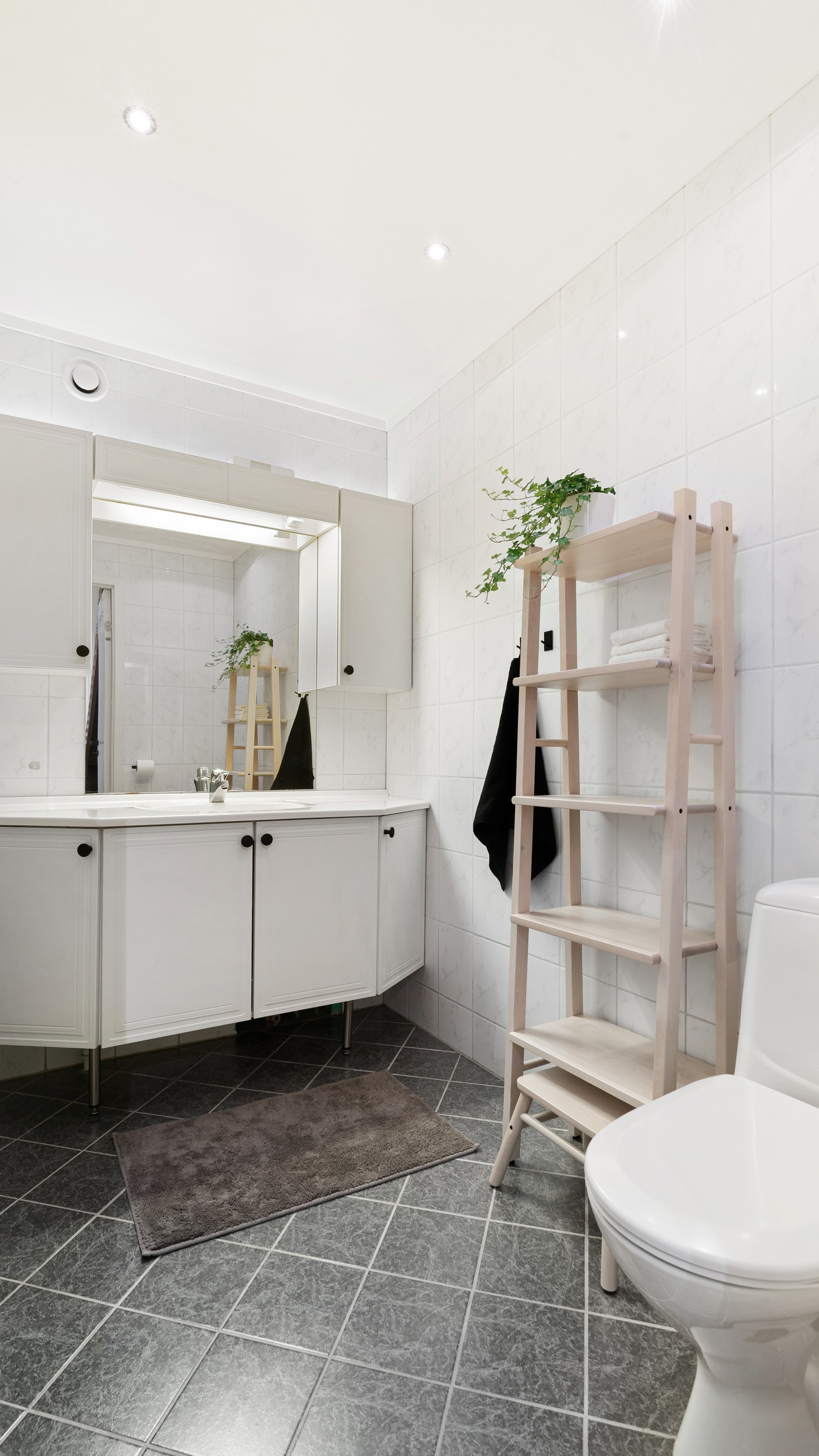 Badet fremstår romslig med dusjhjørne og stor baderomsinnredning med overspeil.