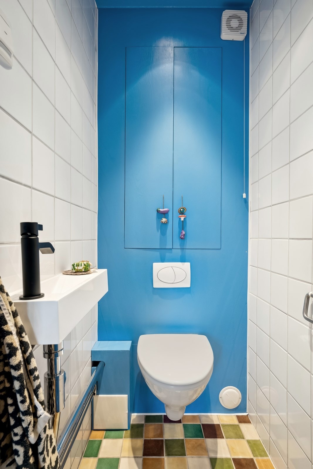 Det praktisk separate toalettet er flislagt i samme utførelse som badet og med delvis malte flater på vegg. Det er downlights i tak og den enkle innredningen består av et vegghengt toalett, samt en servant av mindre modell. Galleribilde