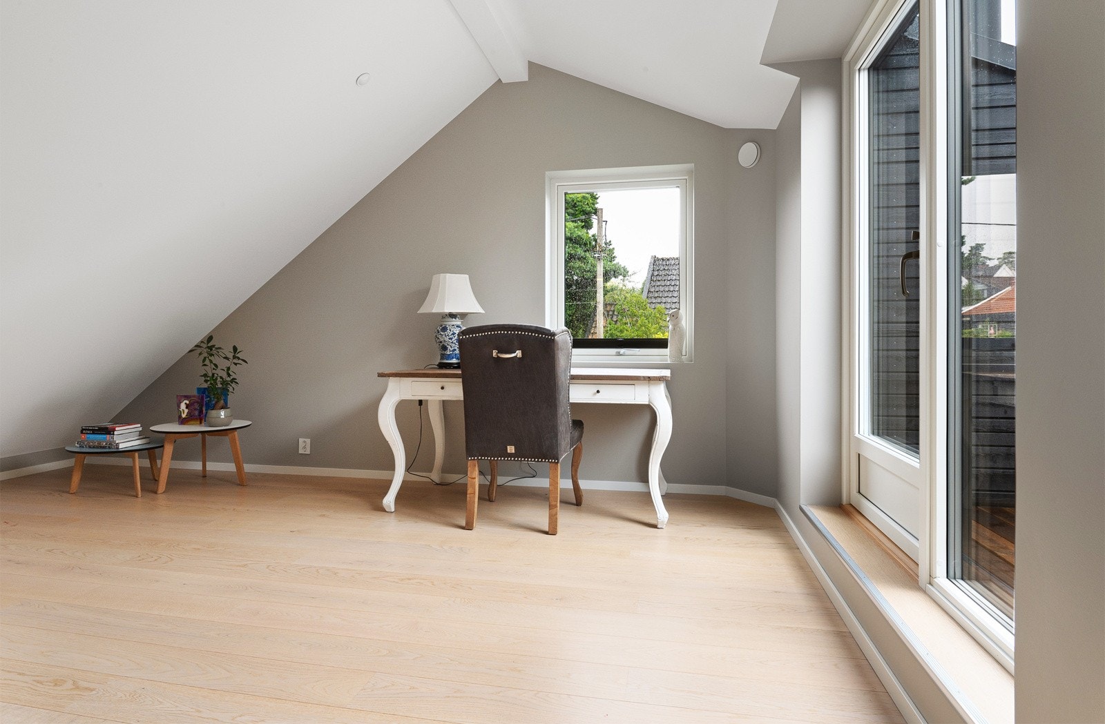 Rommet har skrå himling som gir takhøyde til 2,7 meter, enstavs parkett og glatte veggflater i en varm gråtone som går igjen i øvrige stuer. Galleribilde