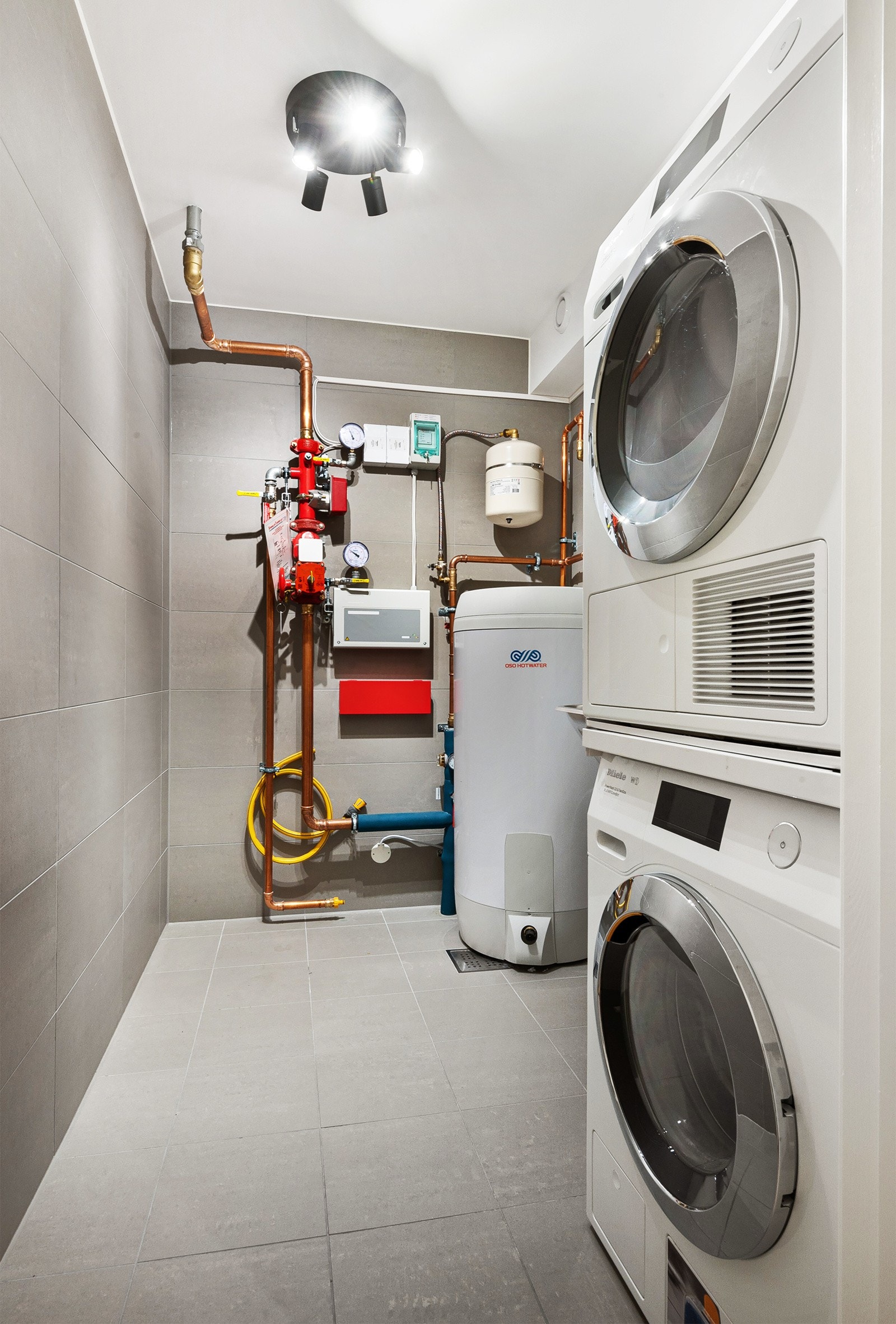 Vaskerommet ligger i kjelleretasjen og har fliser på gulv og vegger, sluk i gulv, gulvvarme, varmtvannsbereder, vaskekum og opplegg for vaskesøyle. Galleribilde