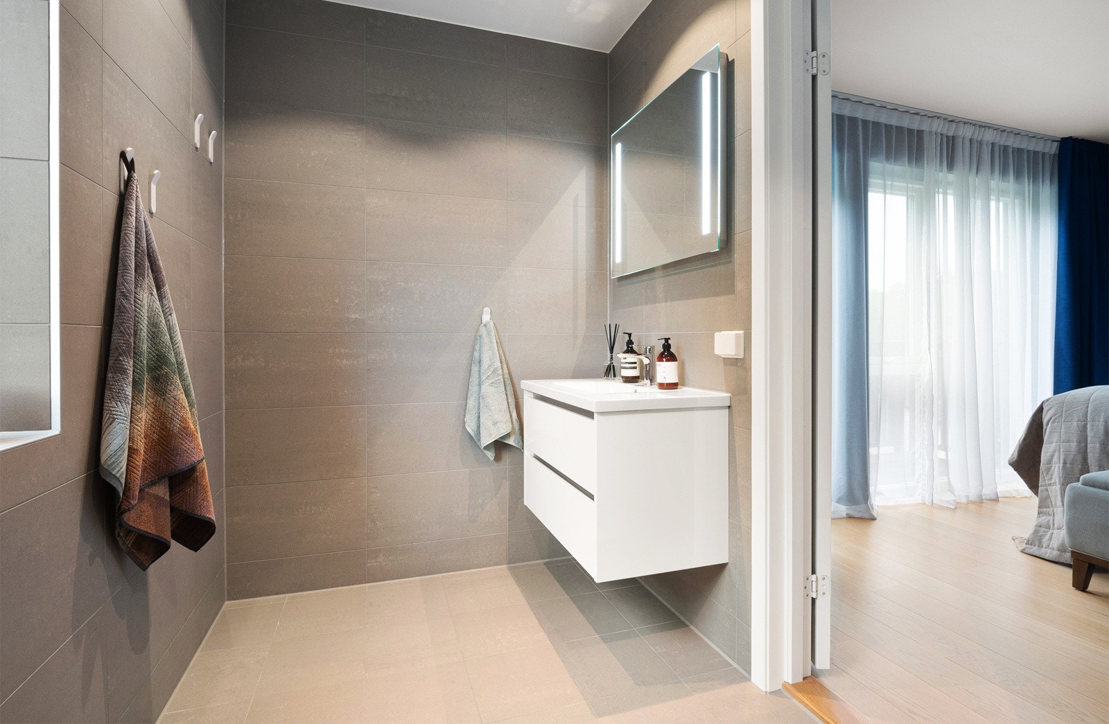 Innredningen består av en heldekkende servant på hvit skuffeseksjon, speil med integrert belysning og et veggmontert toalett. Galleribilde