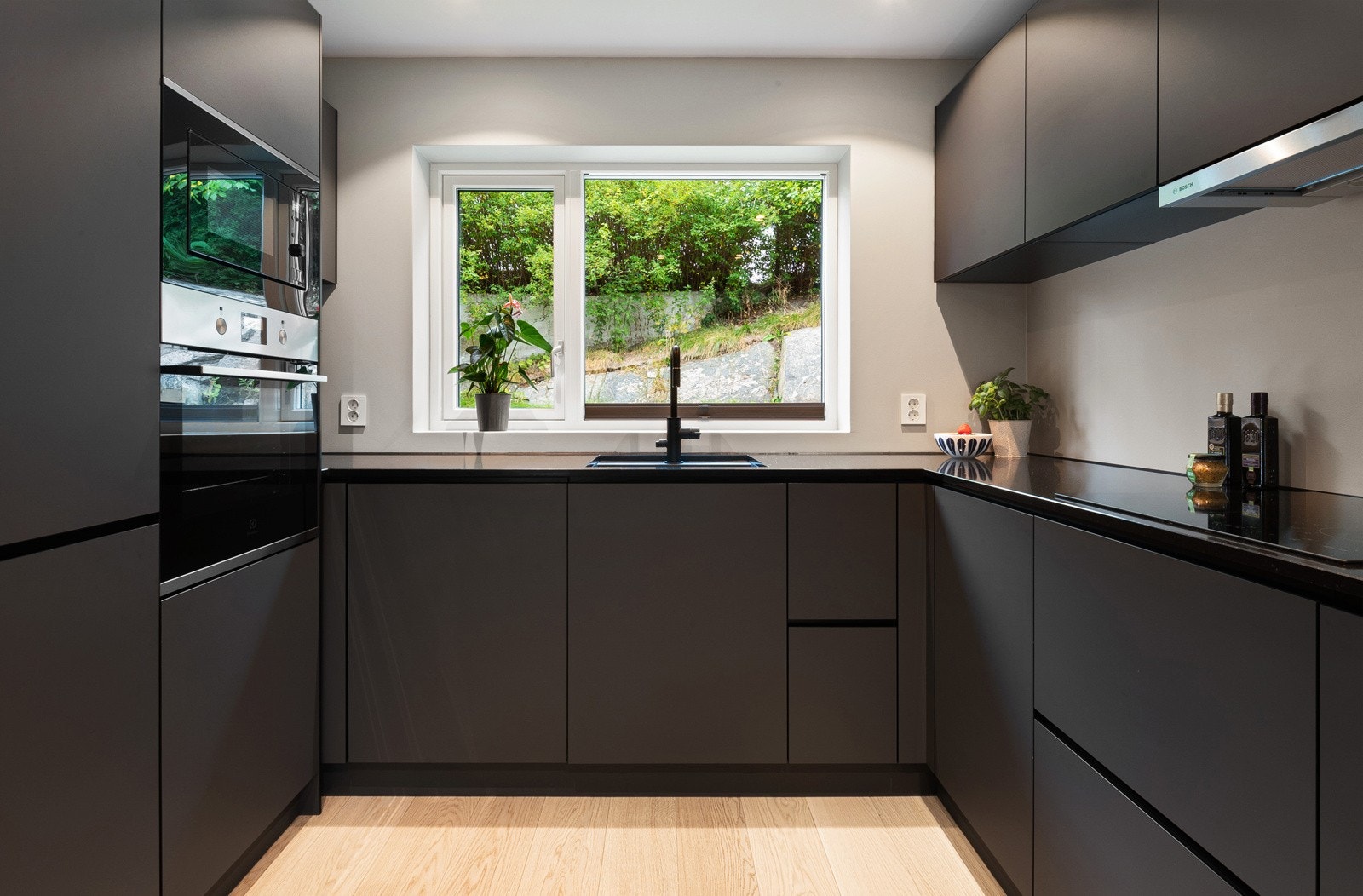 Innredningen har koksgrå, matte fronter, benkeplate i sort kompositt med underlimt, matchende vaskekum og sort kran. Galleribilde