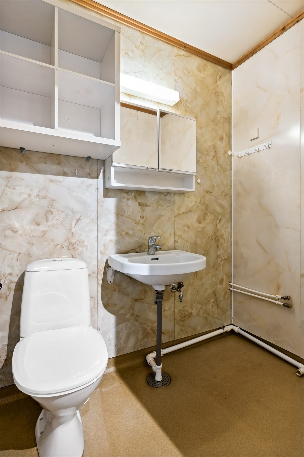 Badet i utleienheten består av gulvbelegg med oppbrett, våtromsplater på vegger og plater i himling. Innredet med baderomsinnredning med servant og toalett. Galleribilde