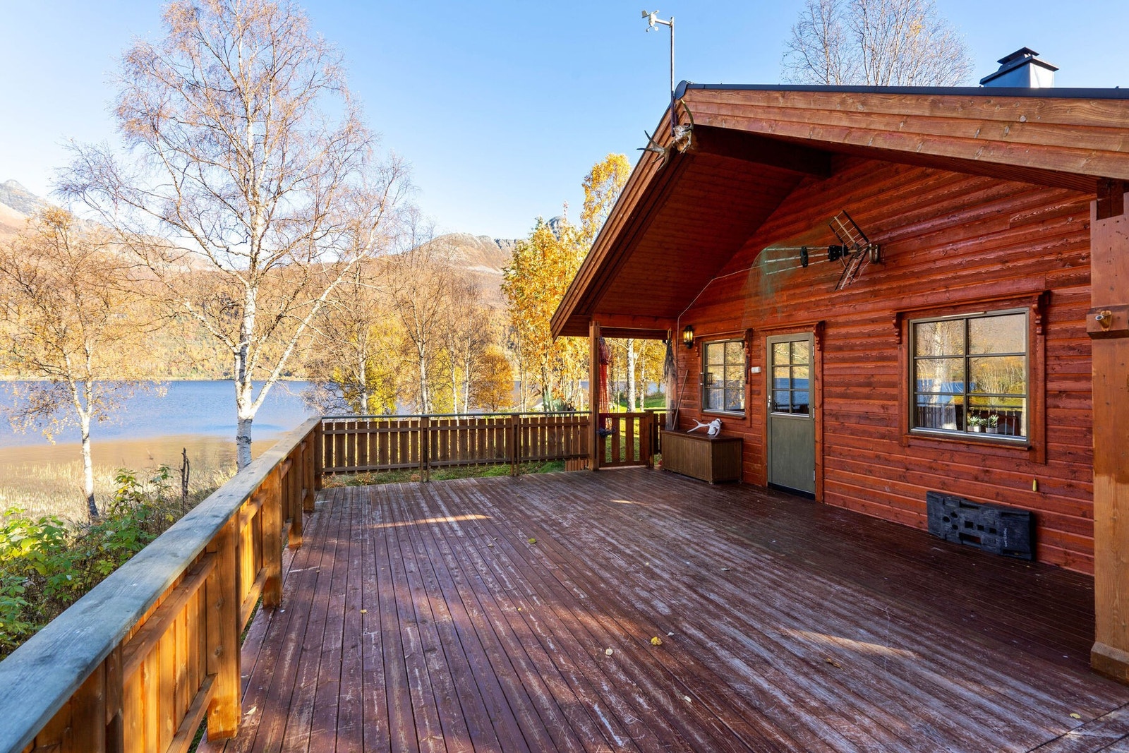 Stor delvis overbygd balkong med utgang i fra stue som går rundt 3 sider av hytta Galleribilde