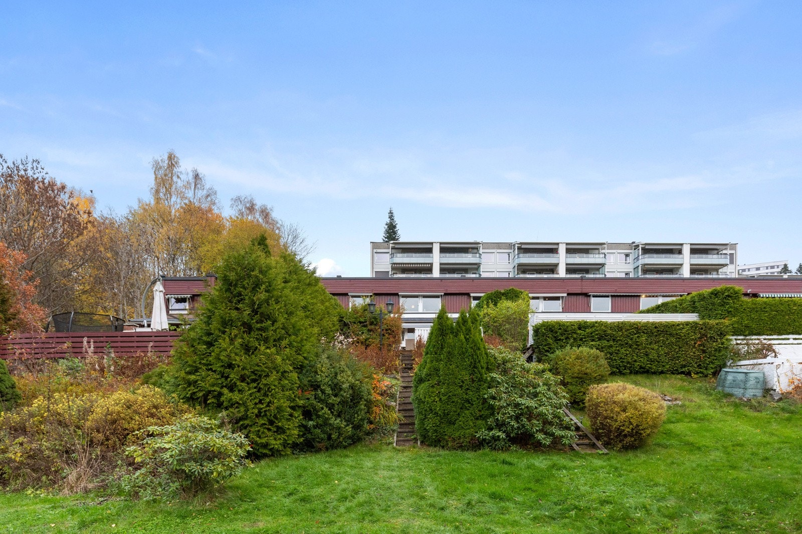 Hage består av en beplantet skråning med bla. rododendron bukser og en gressplen. Galleribilde