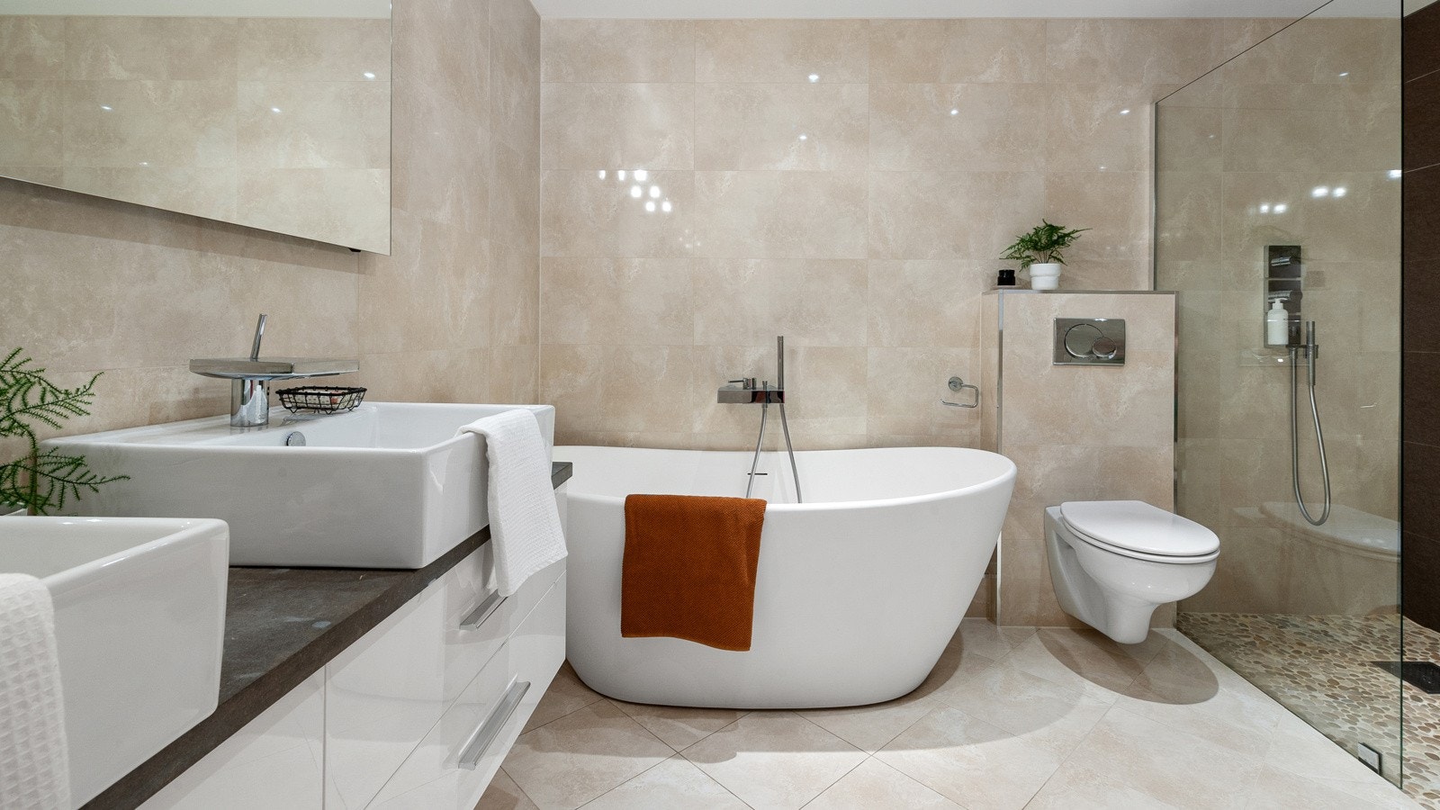 Det stilfulle badet inneholder dobbel servant med møblement, robust benkeplate i stein, speil, belysning og vegghengt toalett. Vasker og dusj er fra den franske designeren Philippe Starck og det er innebygget speil med lys samt duggfjerner. Galleribilde