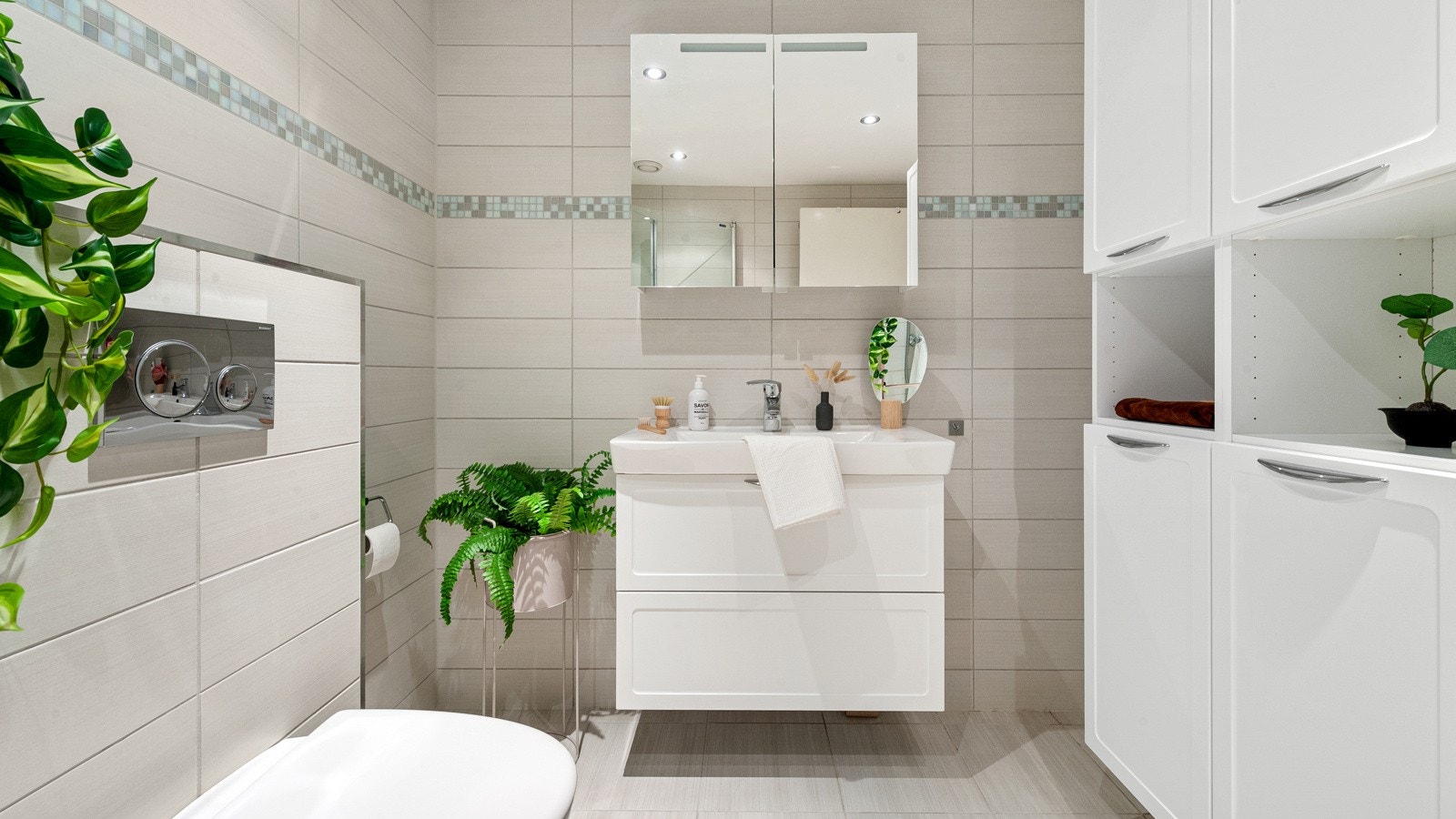 Badet inneholder servant med møblement/speilskap og belysning, to høyskap med god oppbevaring, vegghengt wc, innfellbart dusjhjørne i glass og opplegg for håndklestativ med vannbåren varme. Galleribilde