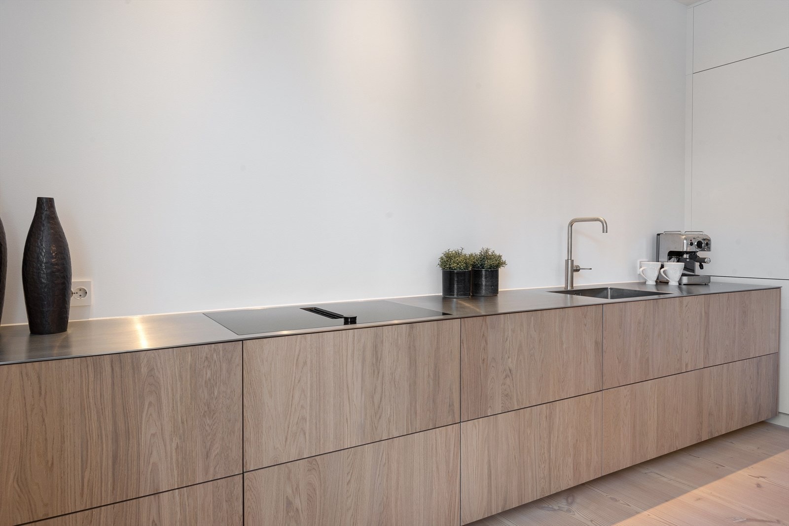 Kjøkkeninnredning fra Drømmekjøkken med lekre fronter i eik, heldekkende stål benkeplate med oppvaskkum og 1-greps blandebatteri fra Vola. Galleribilde