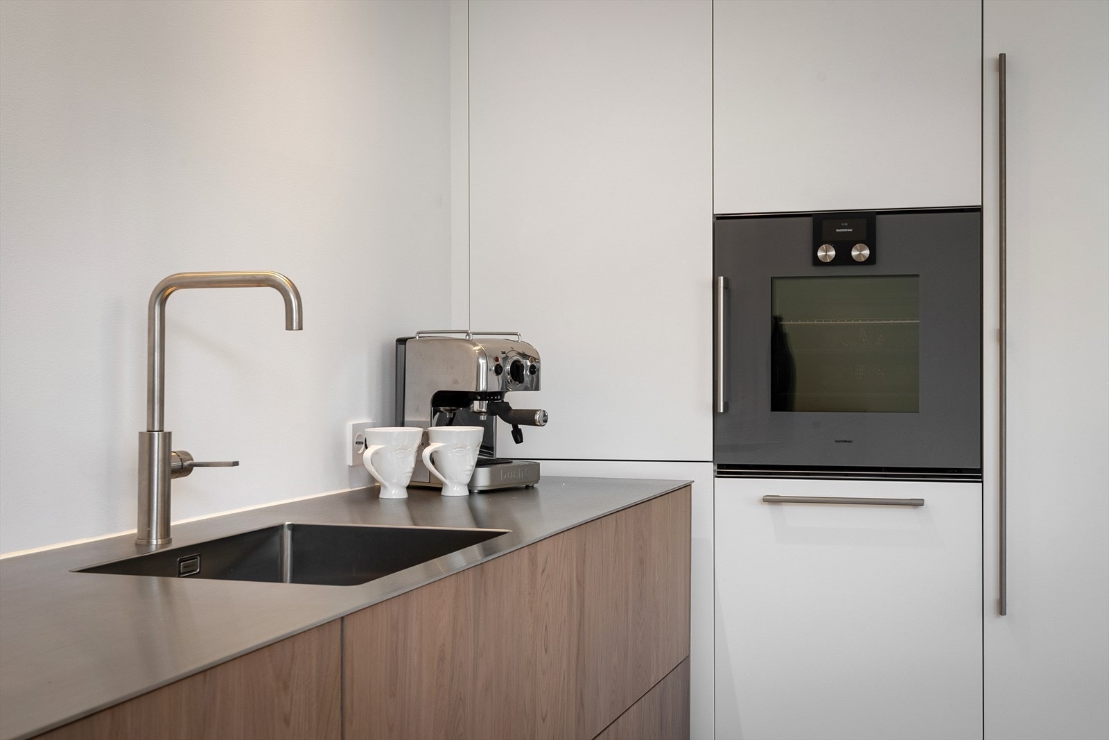 Hvitt snekkertilpasset høyskap med børstede stålgrep og god skapplass. Galleribilde