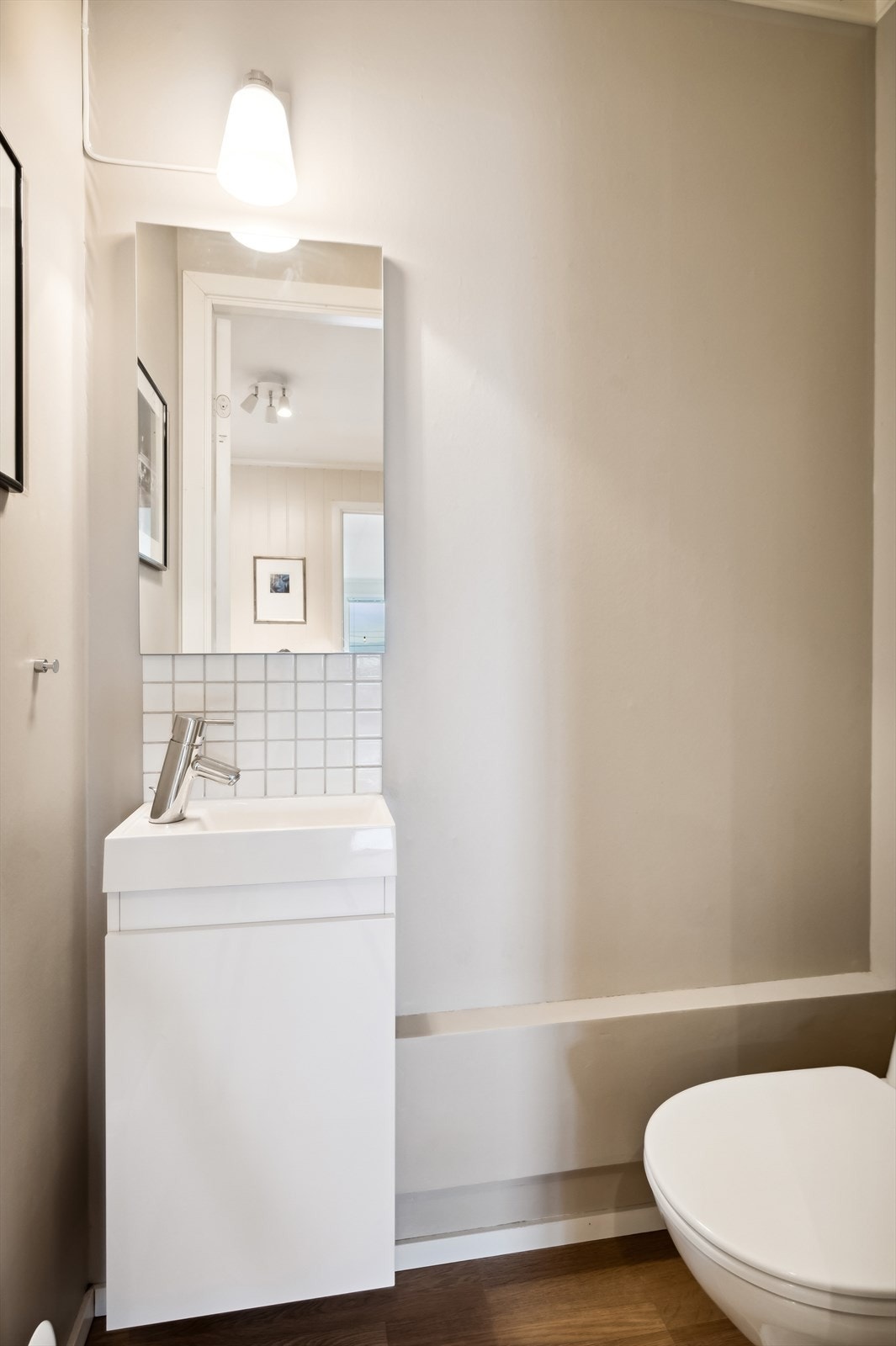 Separat toalettrom bestående av gulvstående klosett og servant med tilhørende benkeskap. Galleribilde