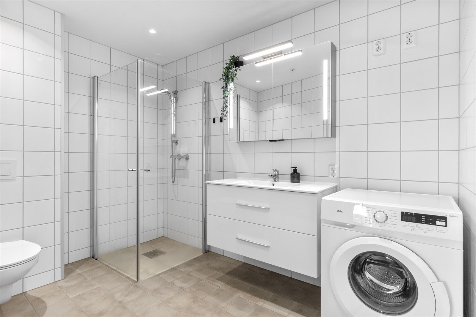 Badet er innredet med vegghengt toalett, dusjnisje, innredning med servant og opplegg til vaskemaskin. Galleribilde