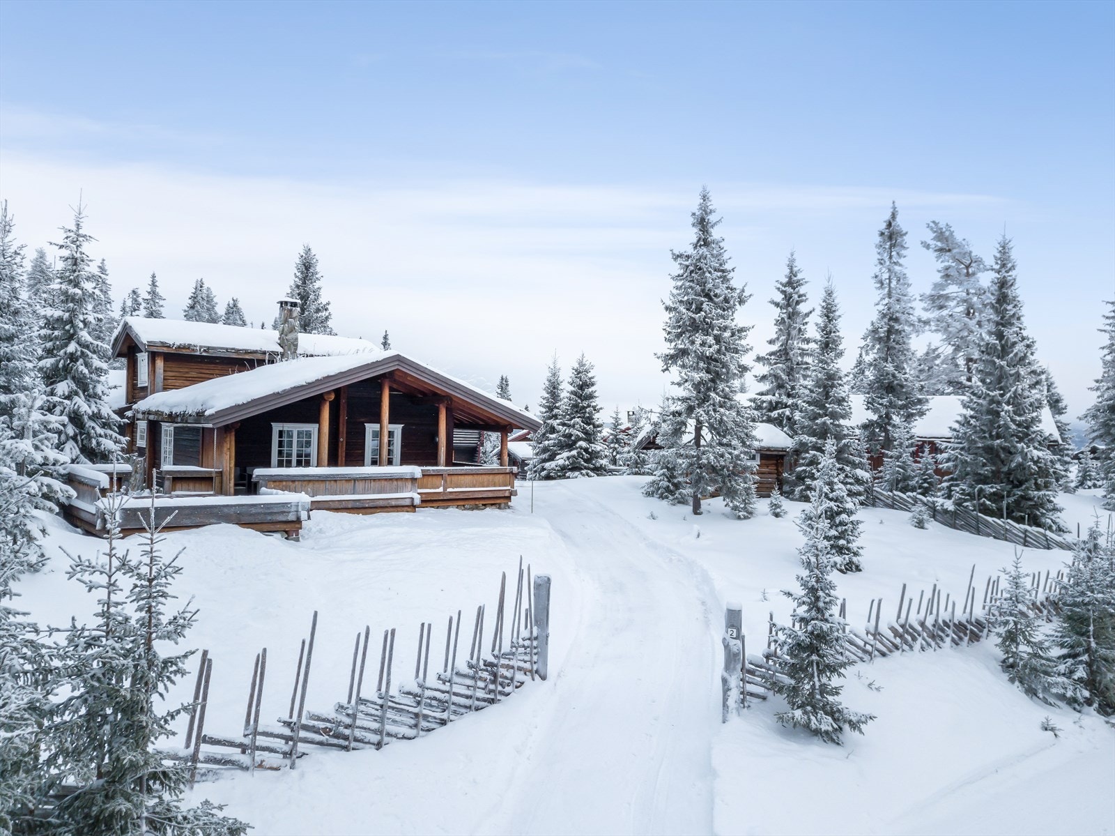 Et sjarmerende hyttetun med laftet tømmerhytte, stabbur og melkebu - Inngjerdet med kledelig skigard. Galleribilde