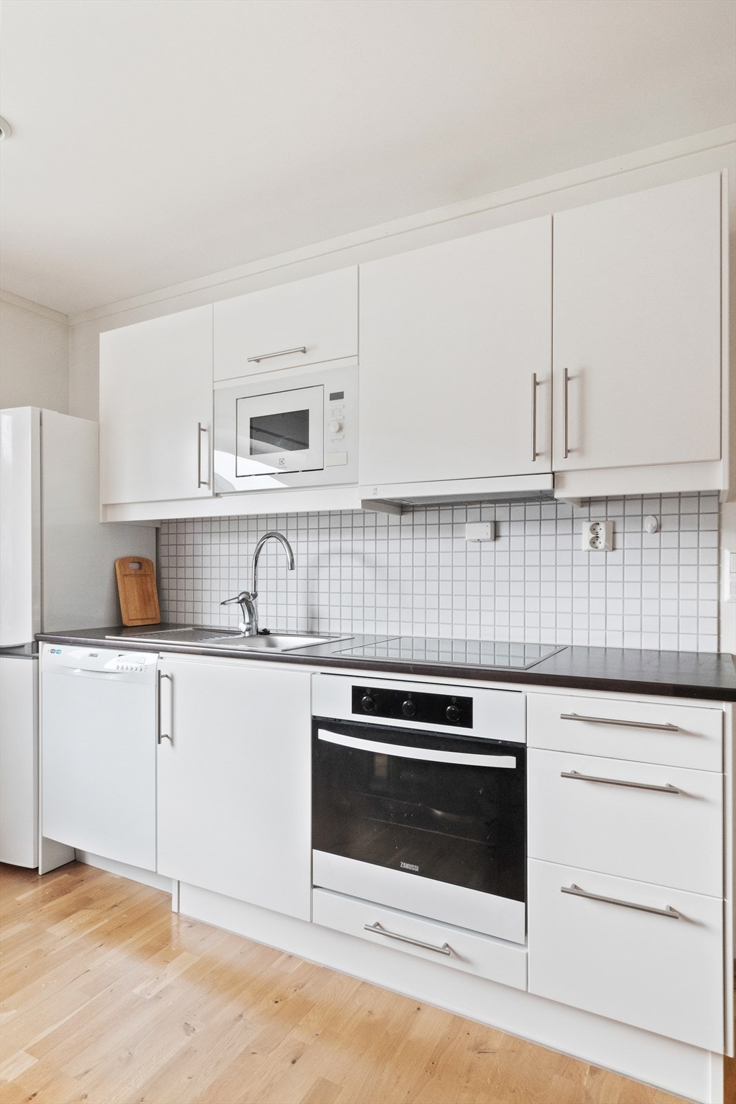 Kjøkkenet har en hvit innredning med god skapplass, som står i stil med resten av leiligheten. Galleribilde