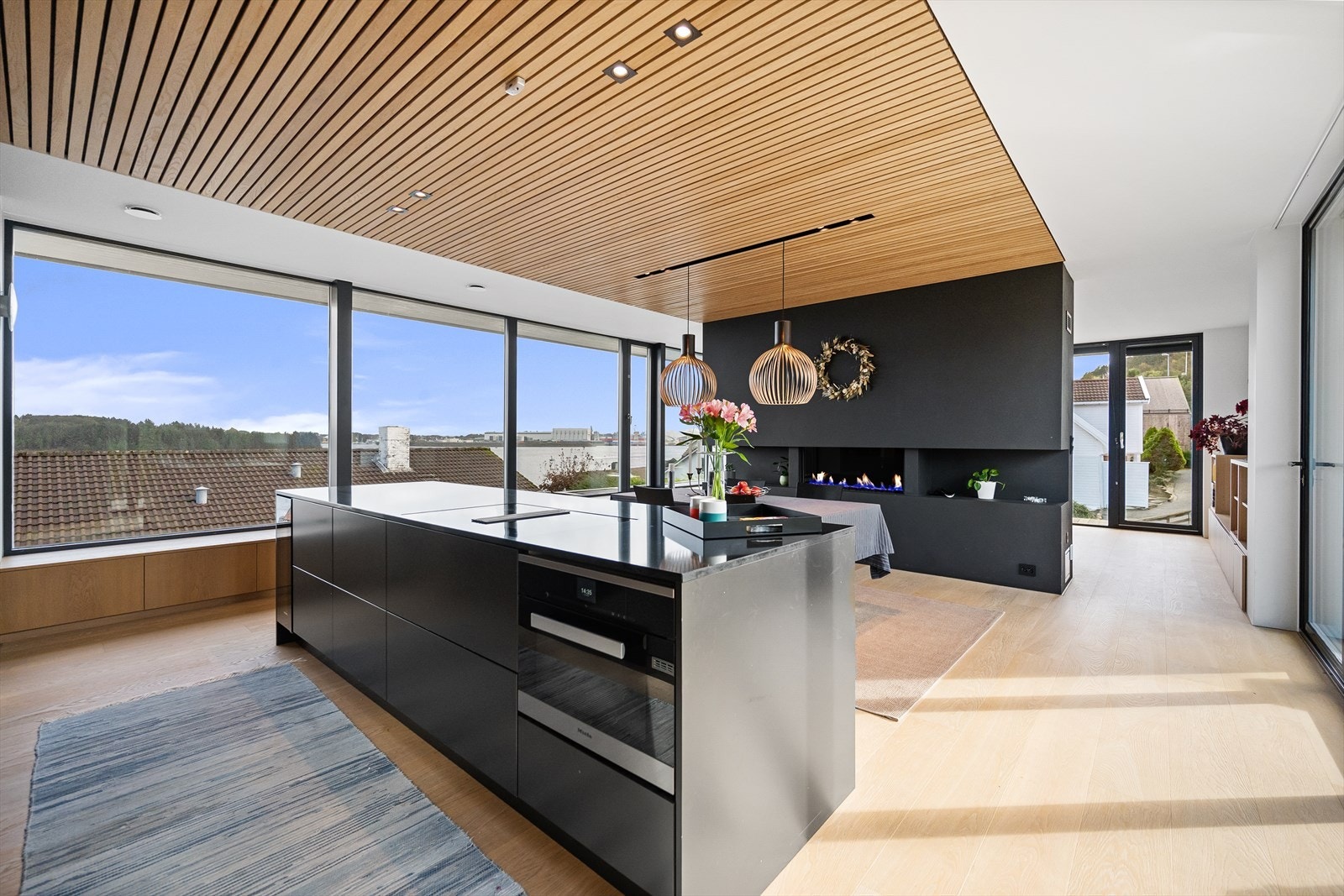 Allrom/kjøkken og spisestuen med takspiler og gasspeis som romdeler Galleribilde