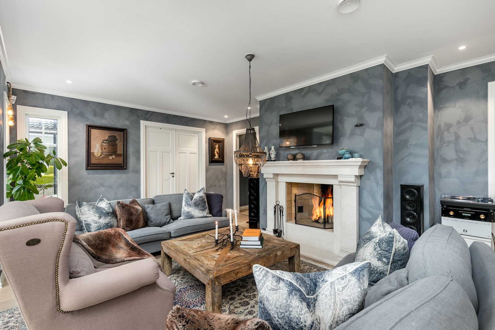 Den flotte peisen i herskapelig stil fremstår som et smykke i det åpne og luftige rommet og gir en lun og behagelig stemning! Her er det god plass for sofaløsning med tilhørende møblement. Galleribilde