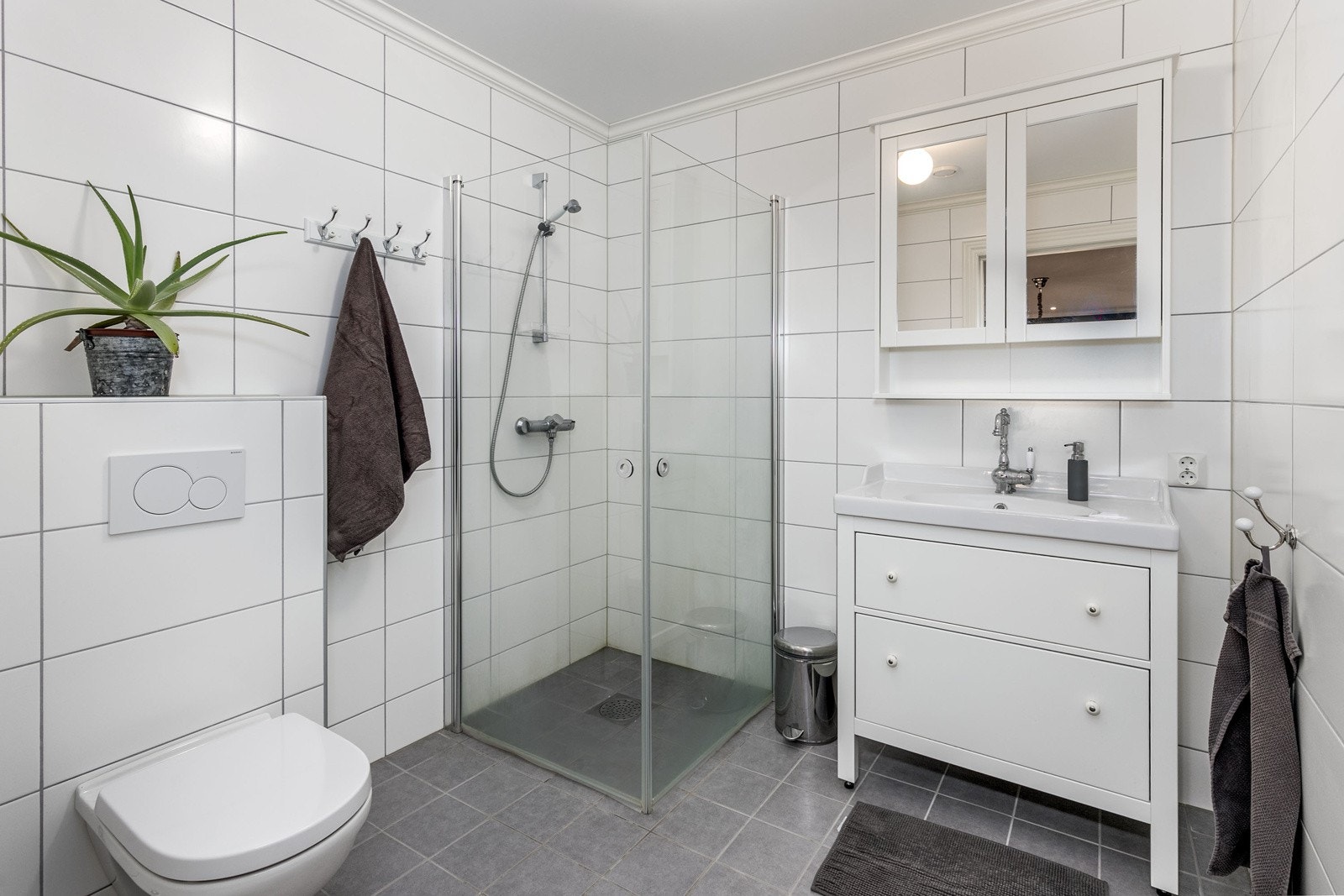 Delikat bad nr. 2 i boligens 2. etasje med flislagte overflater og vannbåren varme i gulv. Badet ligger vegg-i-vegg med soverom 2. Innredningen består av servantmøblement, speil, vegghengt toalett, samt separat dusjhjørne. Galleribilde