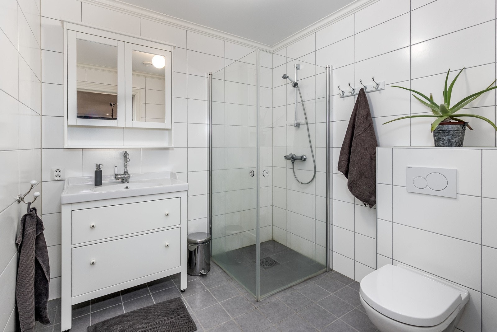 Pent bad nr. 3 i boligens 2. etasje med flislagte overflater og vannbåren varme i gulv. Badet ligger vegg-i-vegg med soverom 3. Innredningen består av servantmøblement, speil, vegghengt toalett, samt separat dusjhjørne. Galleribilde