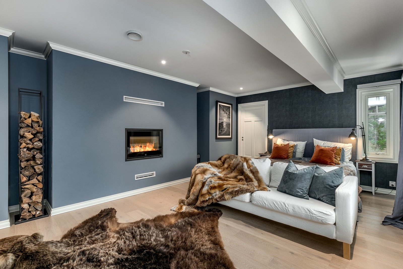 Rommet har malte slette veggflater i en nydelig dempet blåfarge og på gulvet er det lagt nydelig lyspigmentert enstavs parkett. På veggen er det installert en moderne elementpeis som varmer godt på kalde dager. Galleribilde