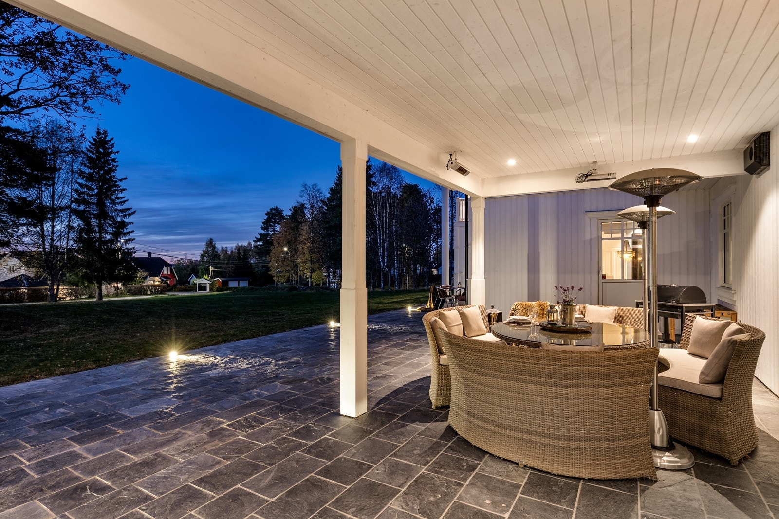 De doble terrassedørene fører enkelt ut til den store skiferbelagte uteplassen på hele 94 kvm som strekker seg rundt store deler av villaen. Her kan man nyte late dager og sene kvelder i skjermede omgivelser. Galleribilde