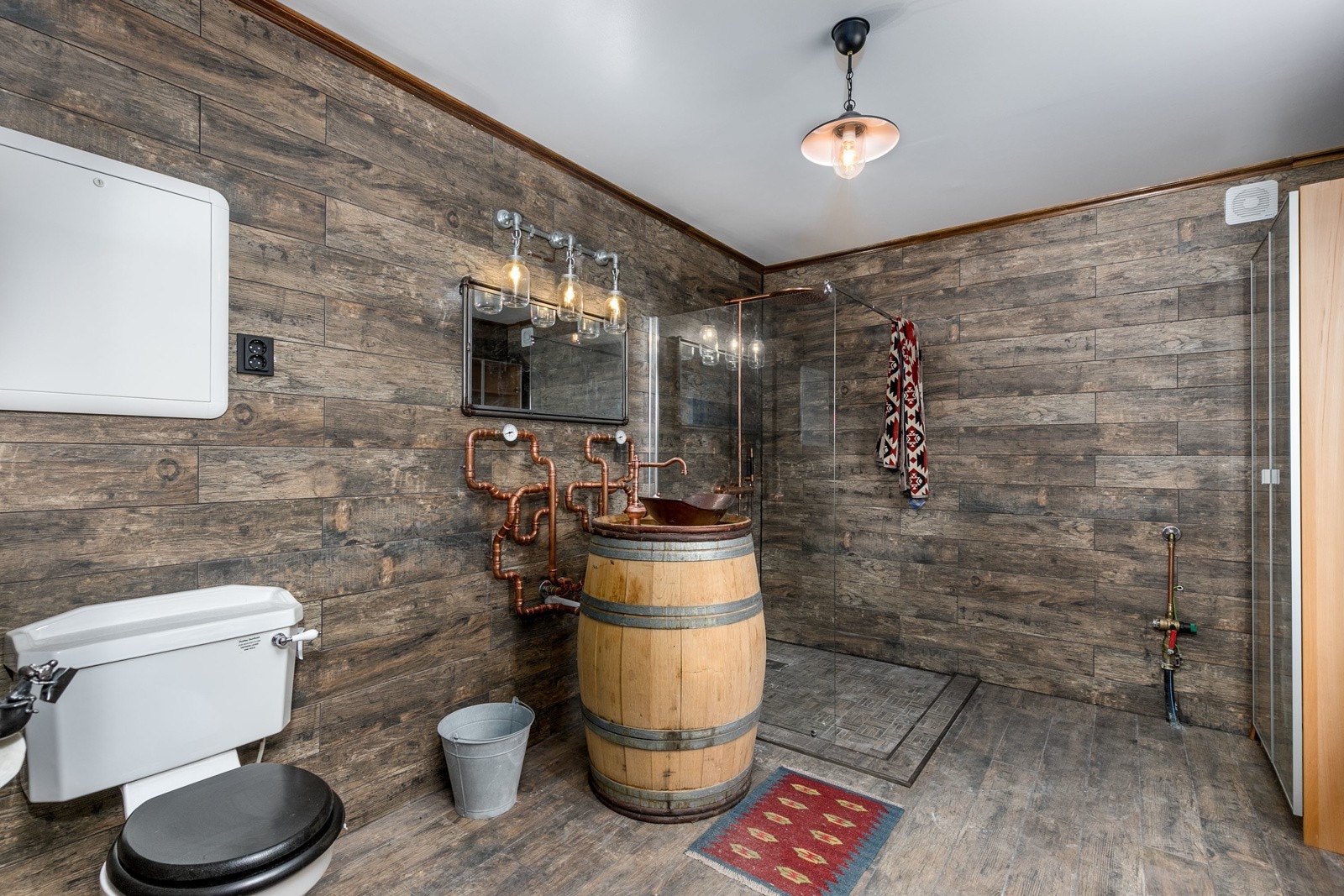 Flislagt baderom med industrielt preg med spesialtilpasset servantløsning m/eldre tønne, toppmontert servant, speil, dusjsone og toalett. Badet har flislagte overflater og vannbåren varme i gulv. Galleribilde