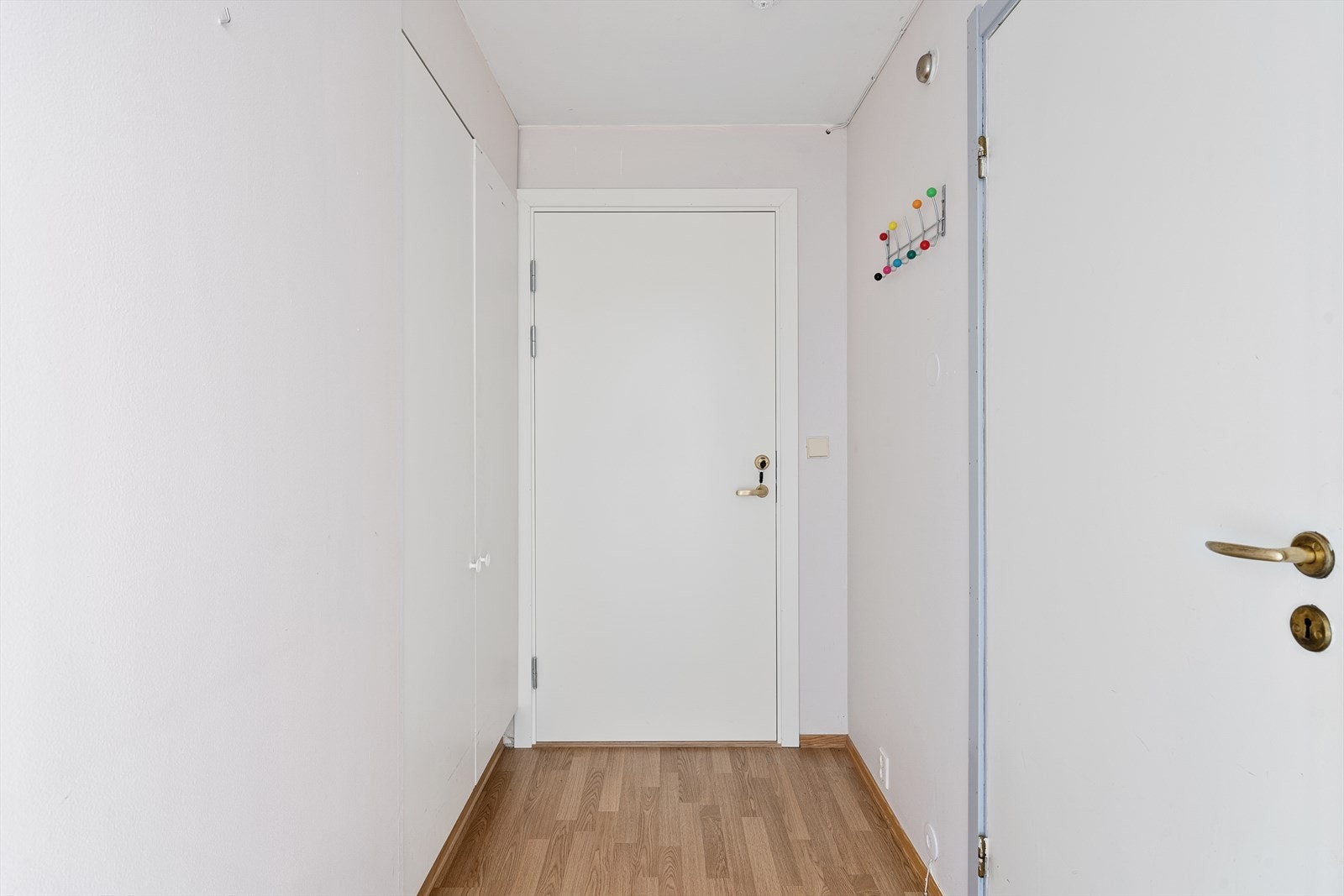 Romslig inngangsparti med god plass til oppbevaring av sko og yttertøy i innebygd garderobe Galleribilde