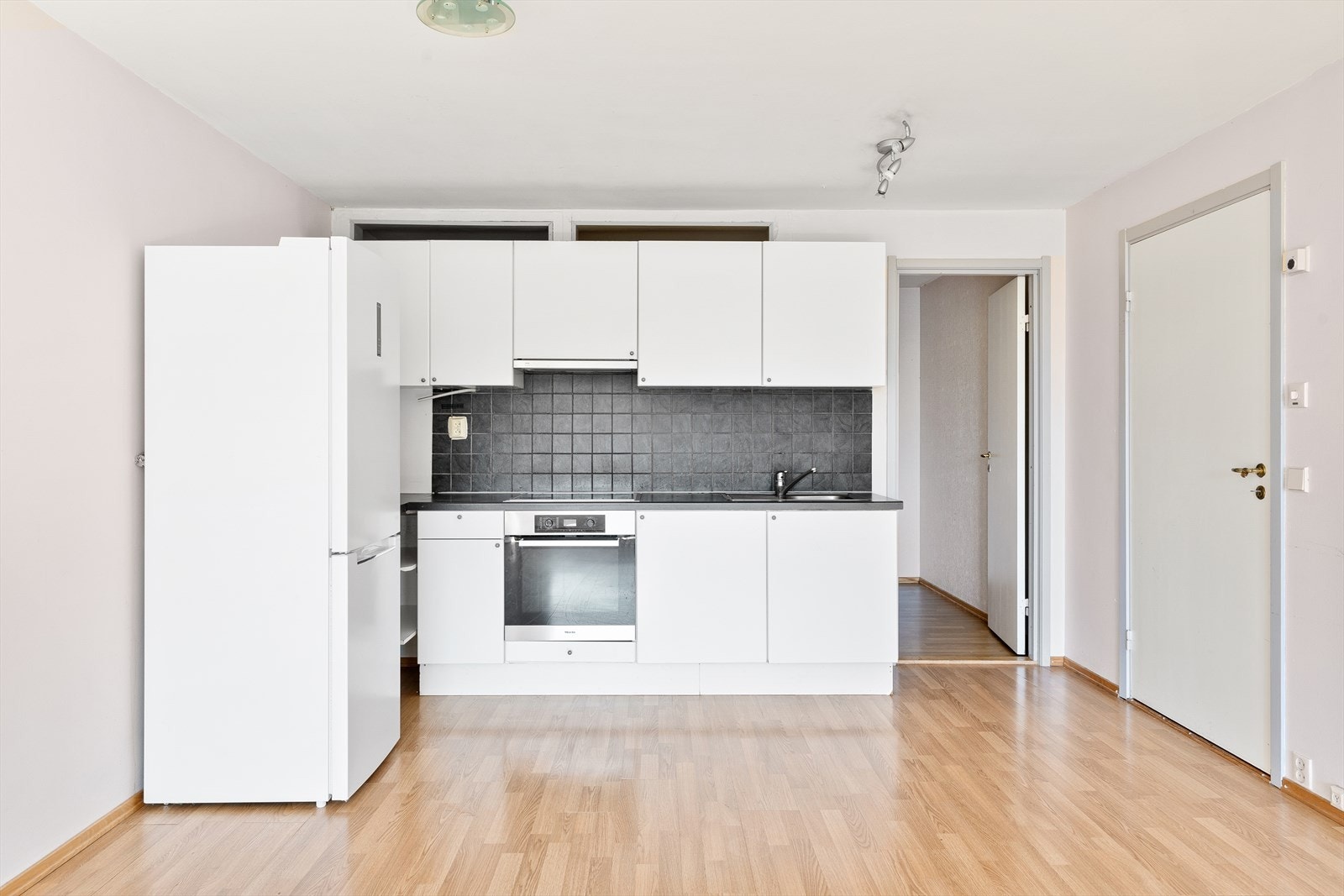 Lyst kjøkken med slette fronter og foliert benkeplate med nedfelt platetopp Galleribilde