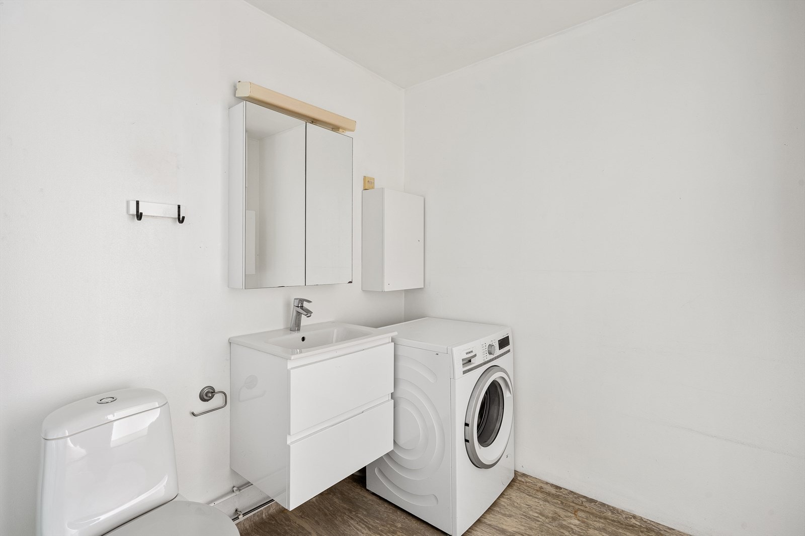 Badet er innredet med dusjkabinett, toalett, servantskap og plass til vaskemaskin Galleribilde