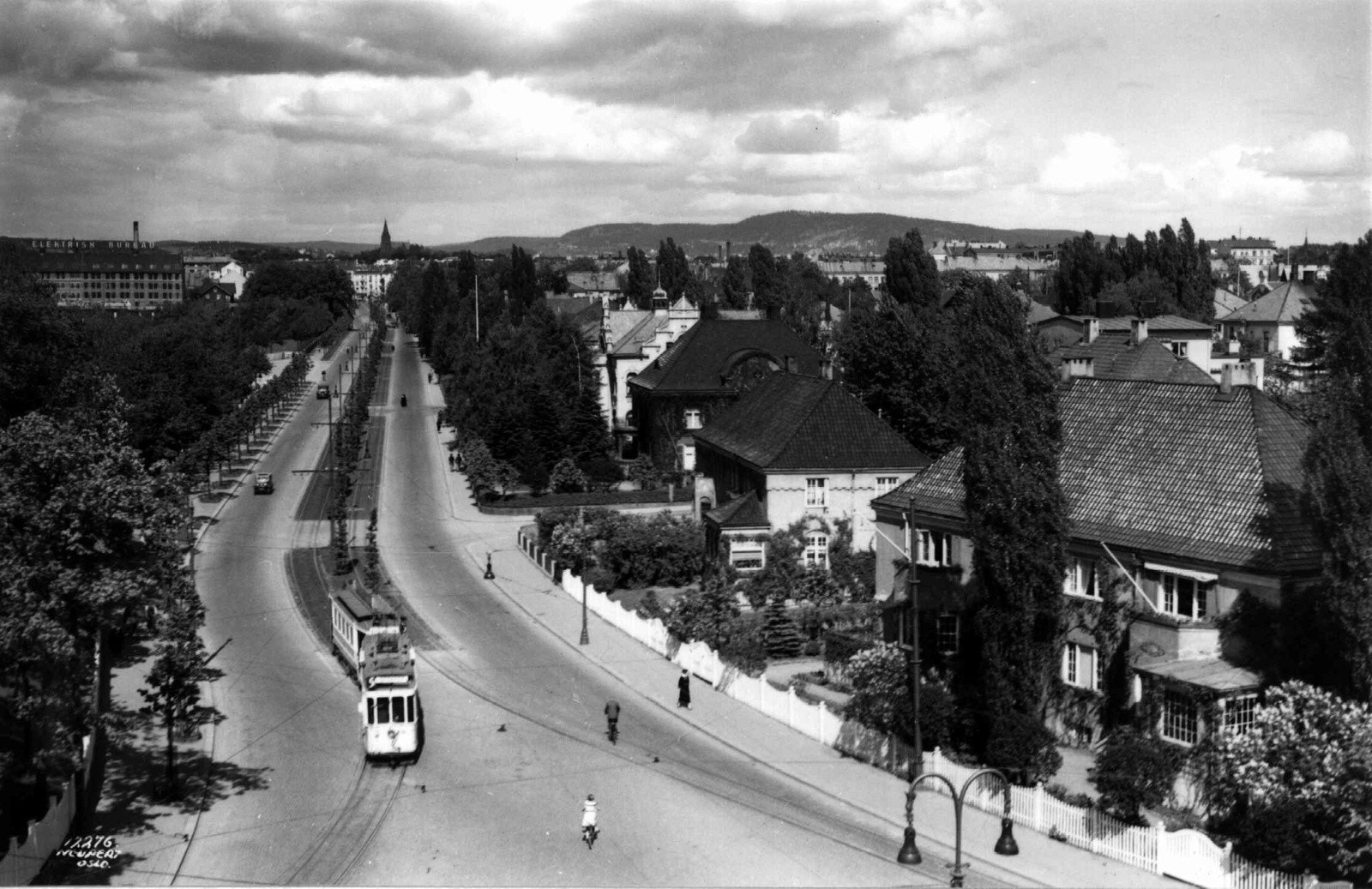 Frogner plass 2. Kirkeveien fra Frogner plass, Oslo 1935. Oversiktsbilde. Gatebilde med trikk, biler, fotgjengere, villaer og Frognerparken. Galleribilde