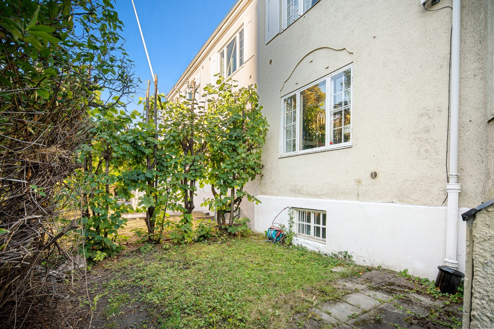 Boligen har en velstelt og flat tomt med brostensbelagt gårdsplass, gressplen, skjermende hekk og frodig prydbeplantning. Galleribilde