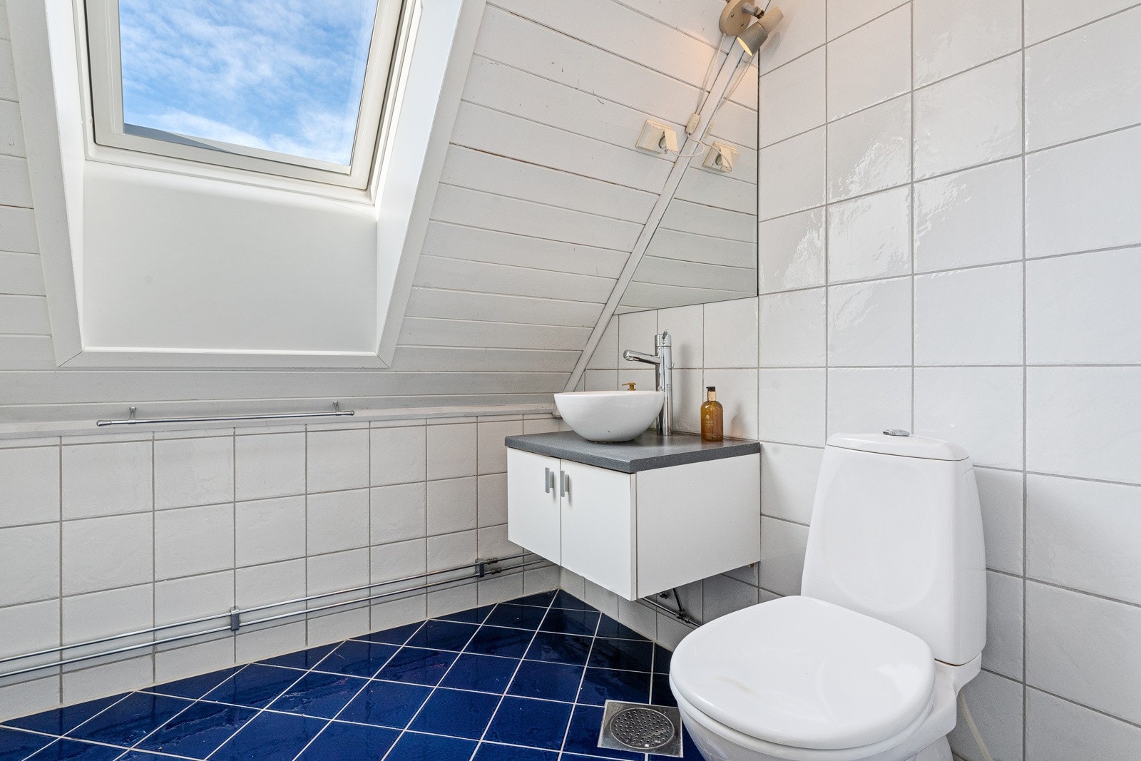 Badet i loftsetasjen var nytt i 2007 og har hvite fliser på veggene, hvitmalt panel i himlingen og blå fliser på gulv med gulvvarme. Galleribilde
