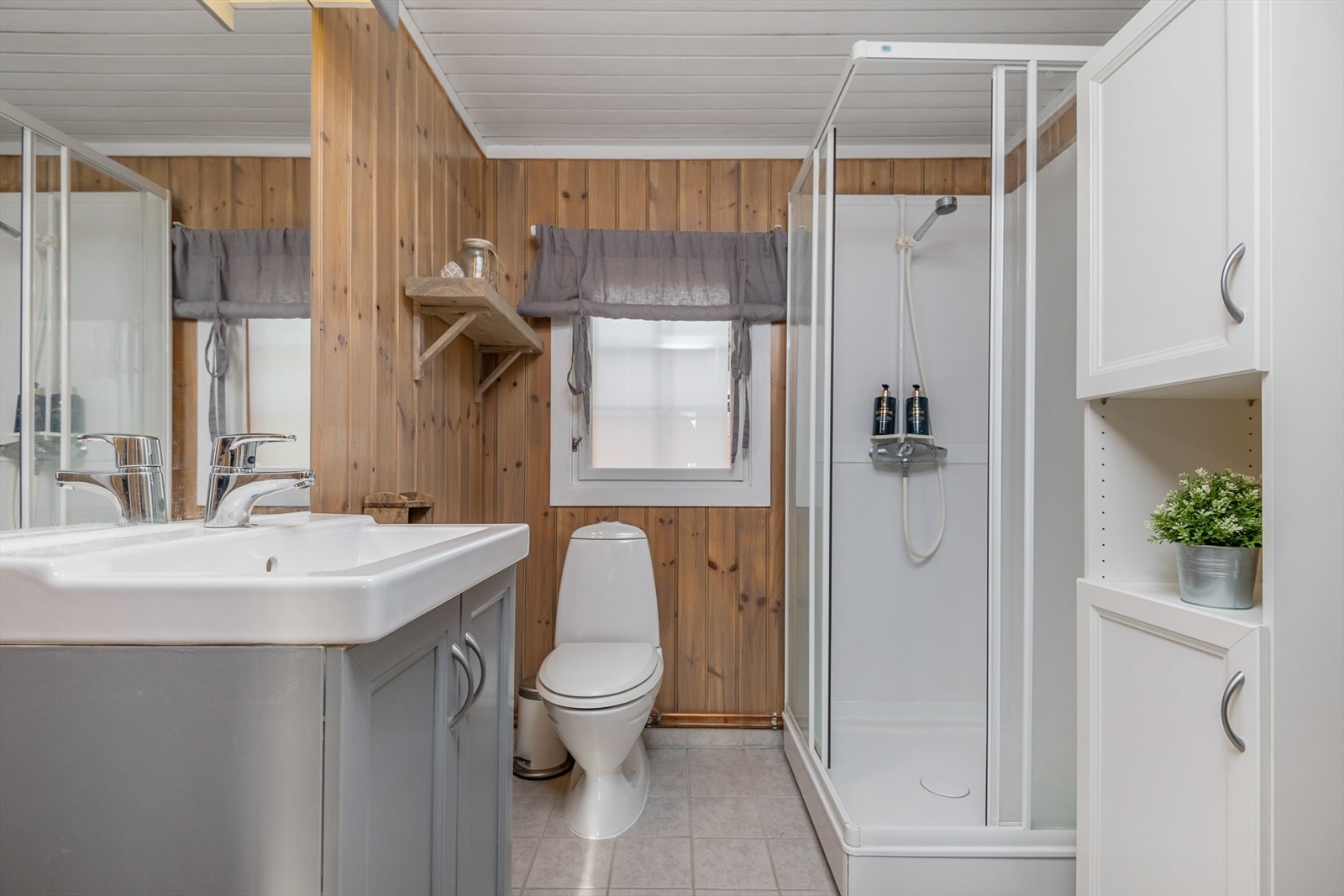 Funksjonelt og stilrent bad/wc med dusjkabinett, wc og servantinnredning. Galleribilde