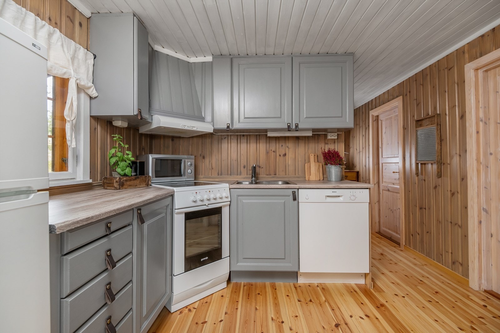 Pent og delikat kjøkken der frontene er malt i en tidløs og lun gråtone. Plass til kjøleskap, oppvaskmaskin og komfyr. Galleribilde